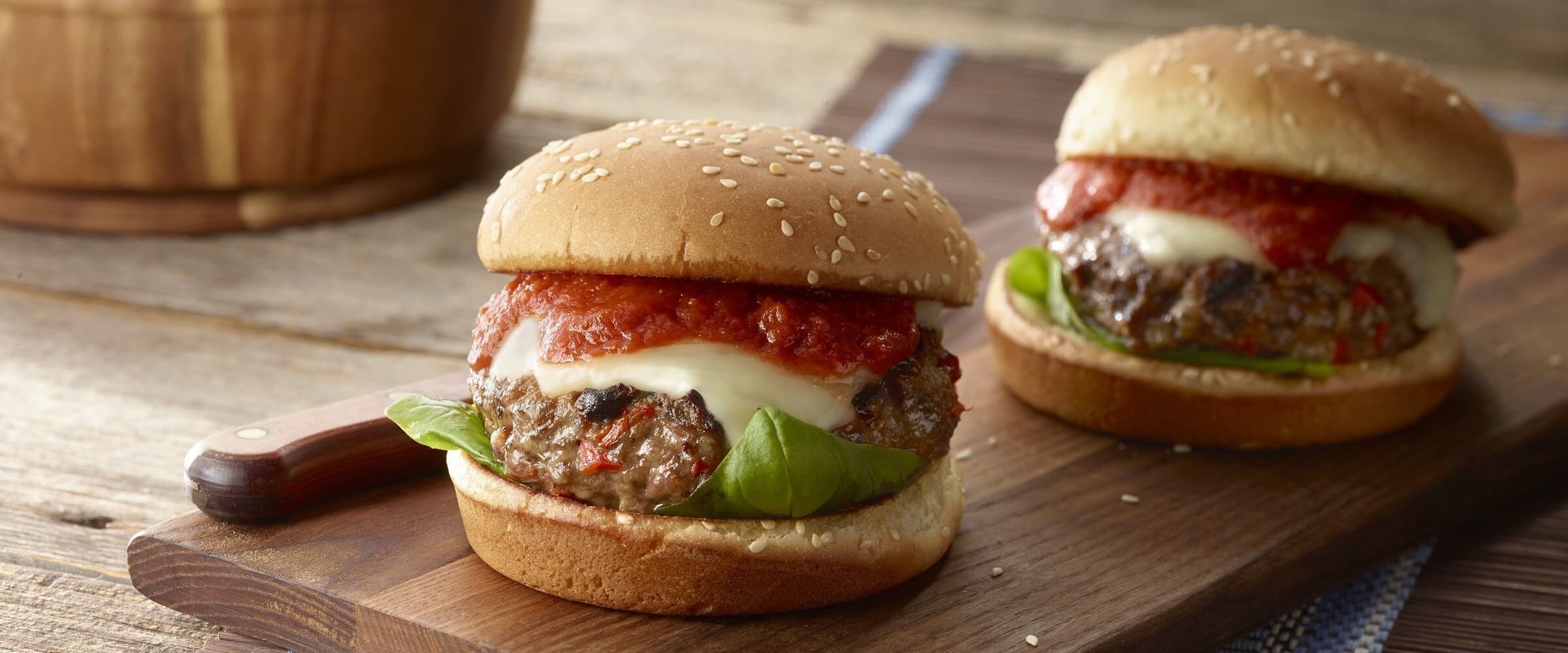 Italian burgers topped with cheese and sauce on wood board