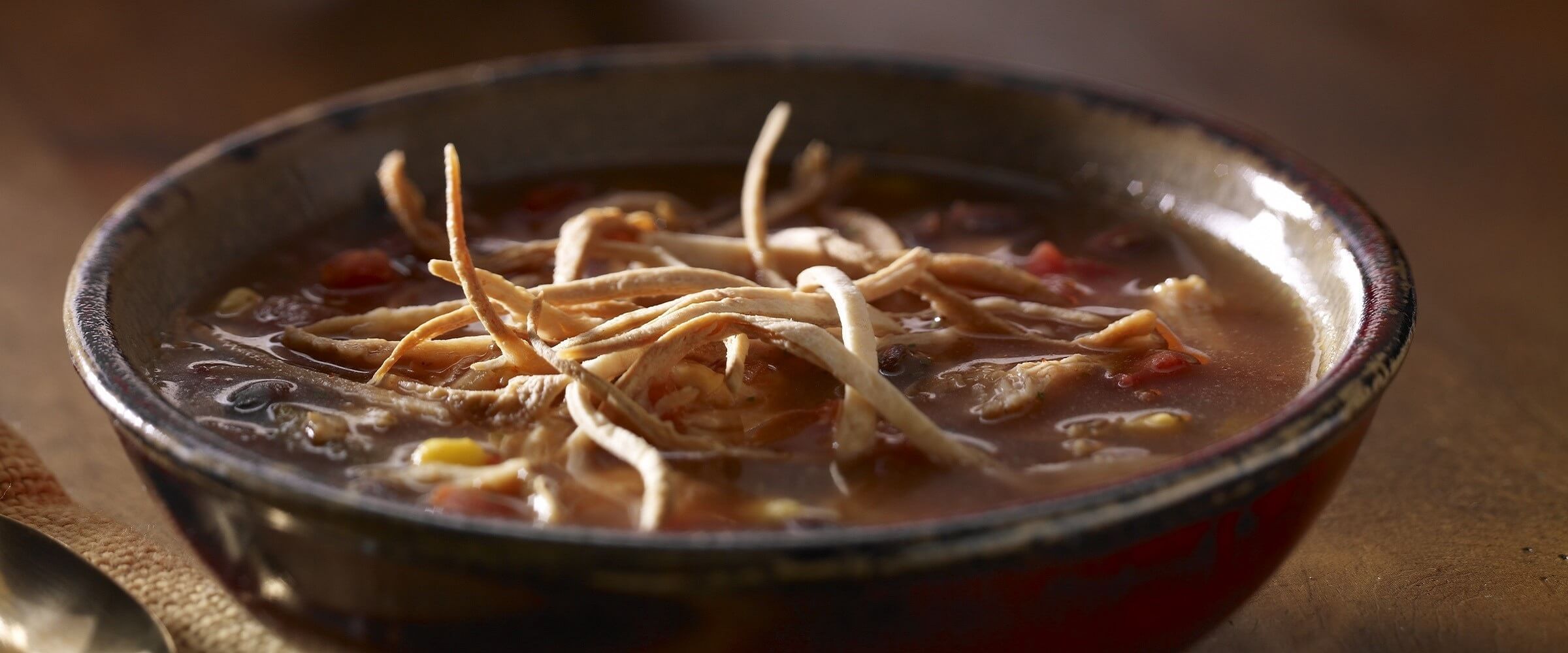 Chicken taco tortilla soup in brown bowl