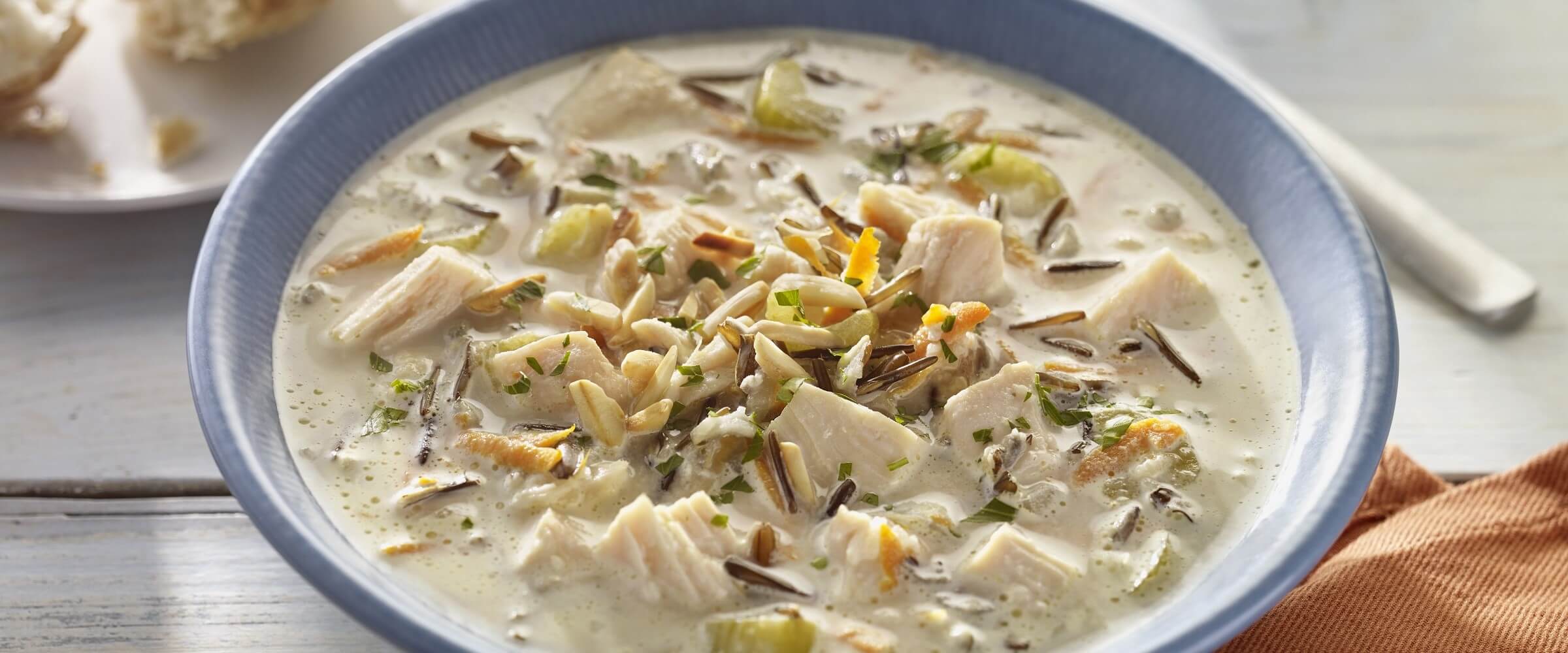 Chicken wild rice soup in blue bowl with orange napkin