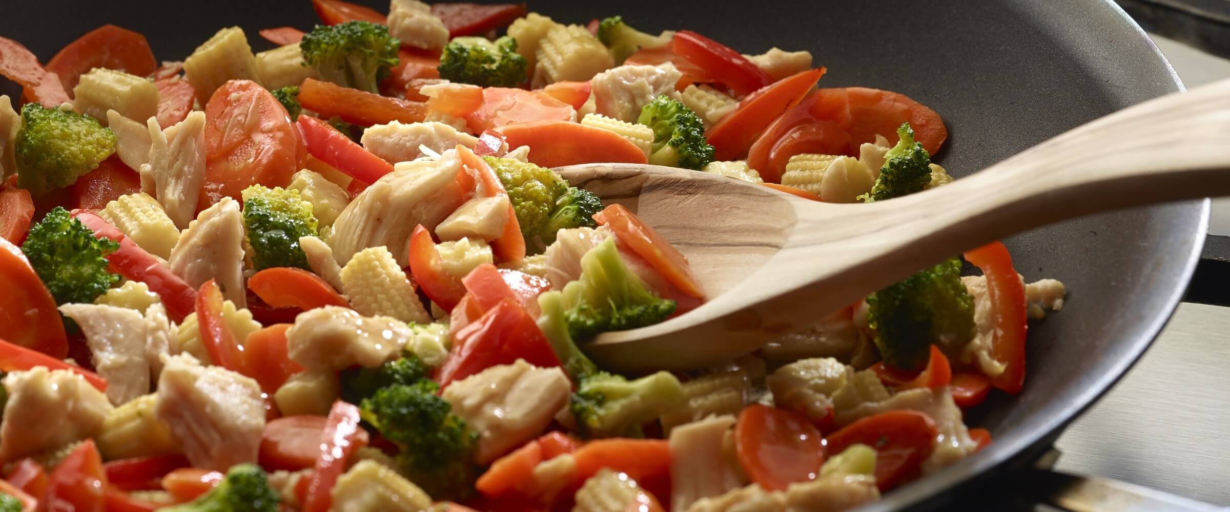 Ginger chicken stir fry with vegetables with wooden spoon in skillet