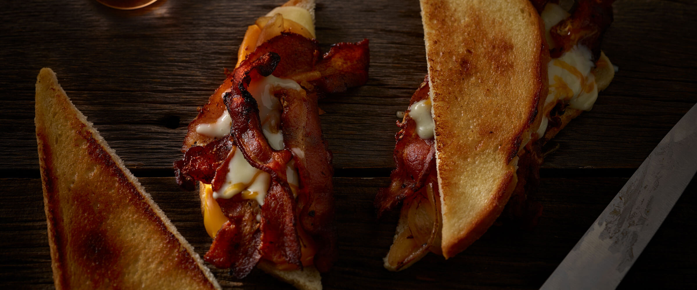 Bacon curd grilled cheese sandwich on wood table