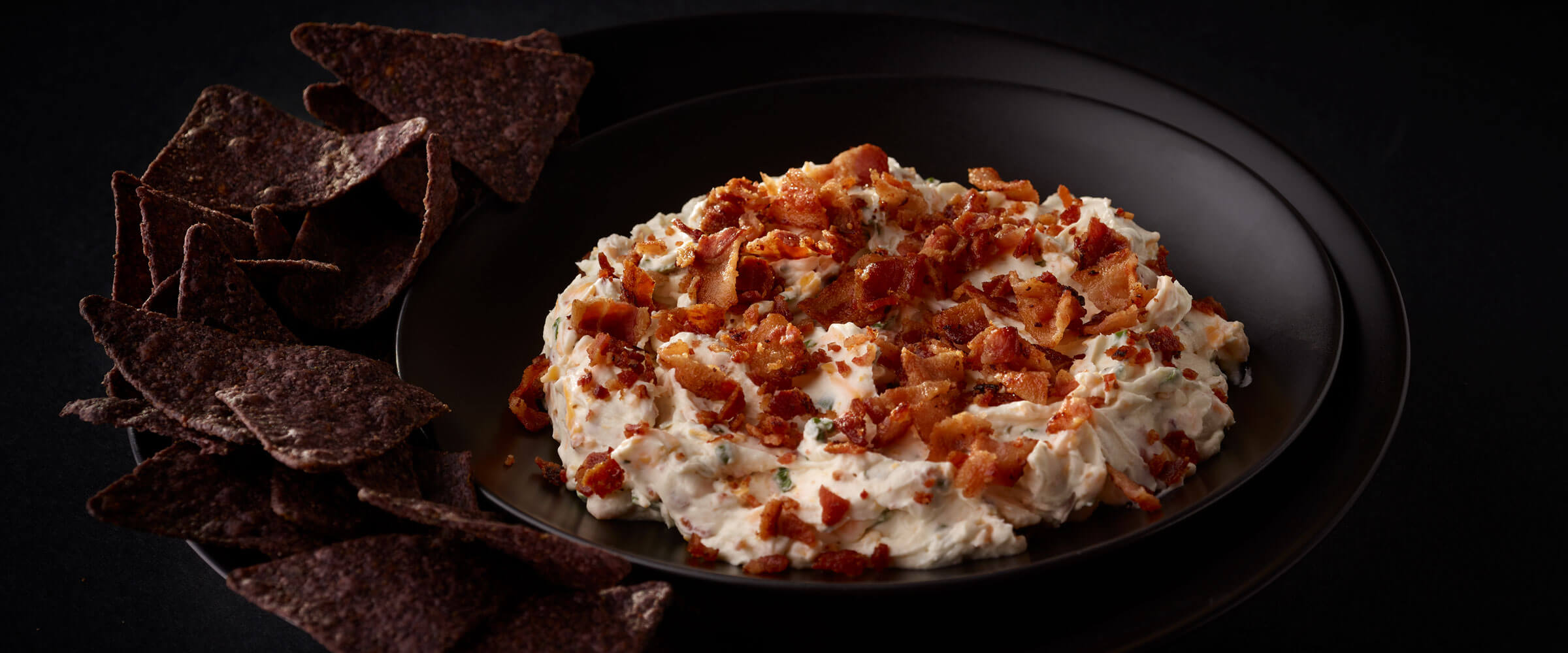 Bacon Ranch dip in black bowl with chips