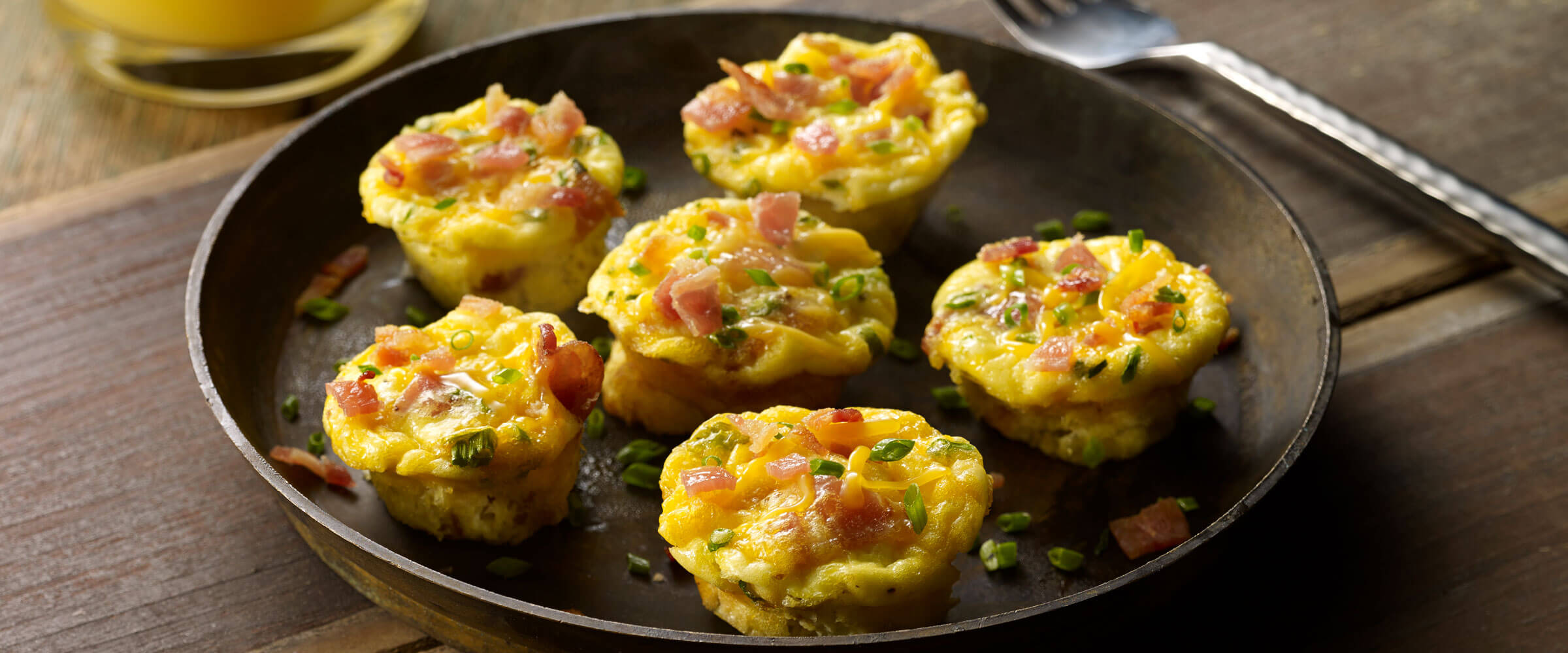 Mini Bacon and Egg Muffins topped with chives on brown plate