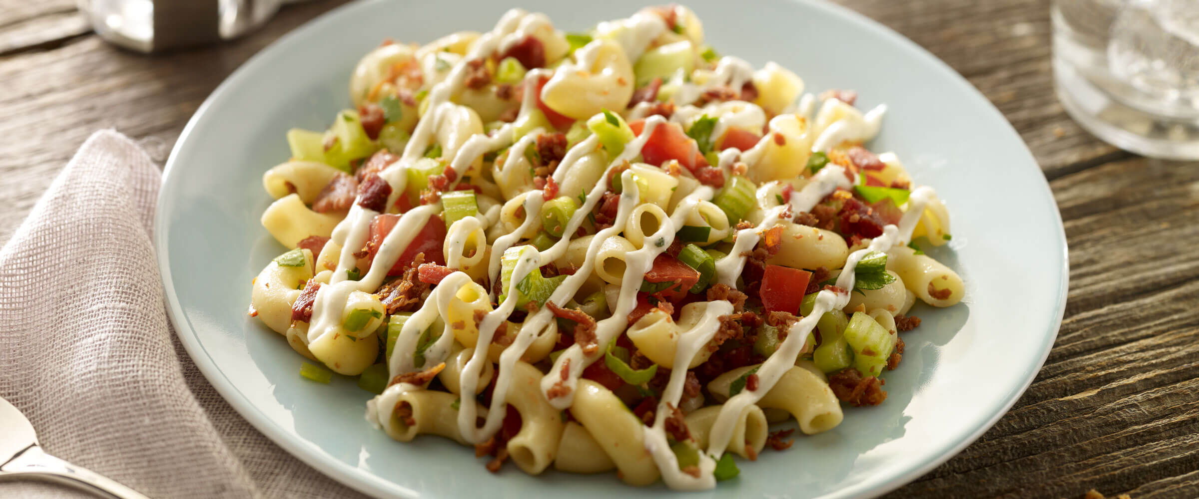 BLT Pasta Salad drizzled with mayo in white bowl