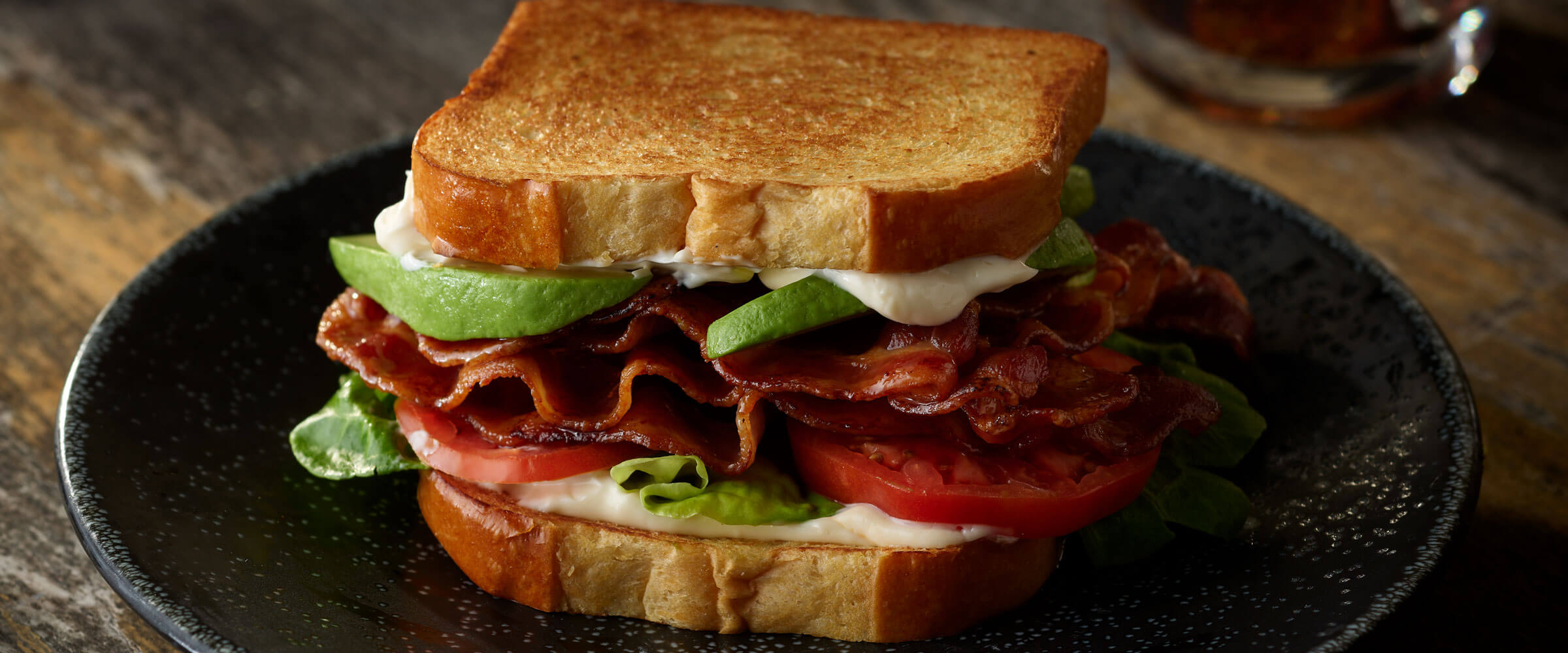 BLT with Avocado on black plae