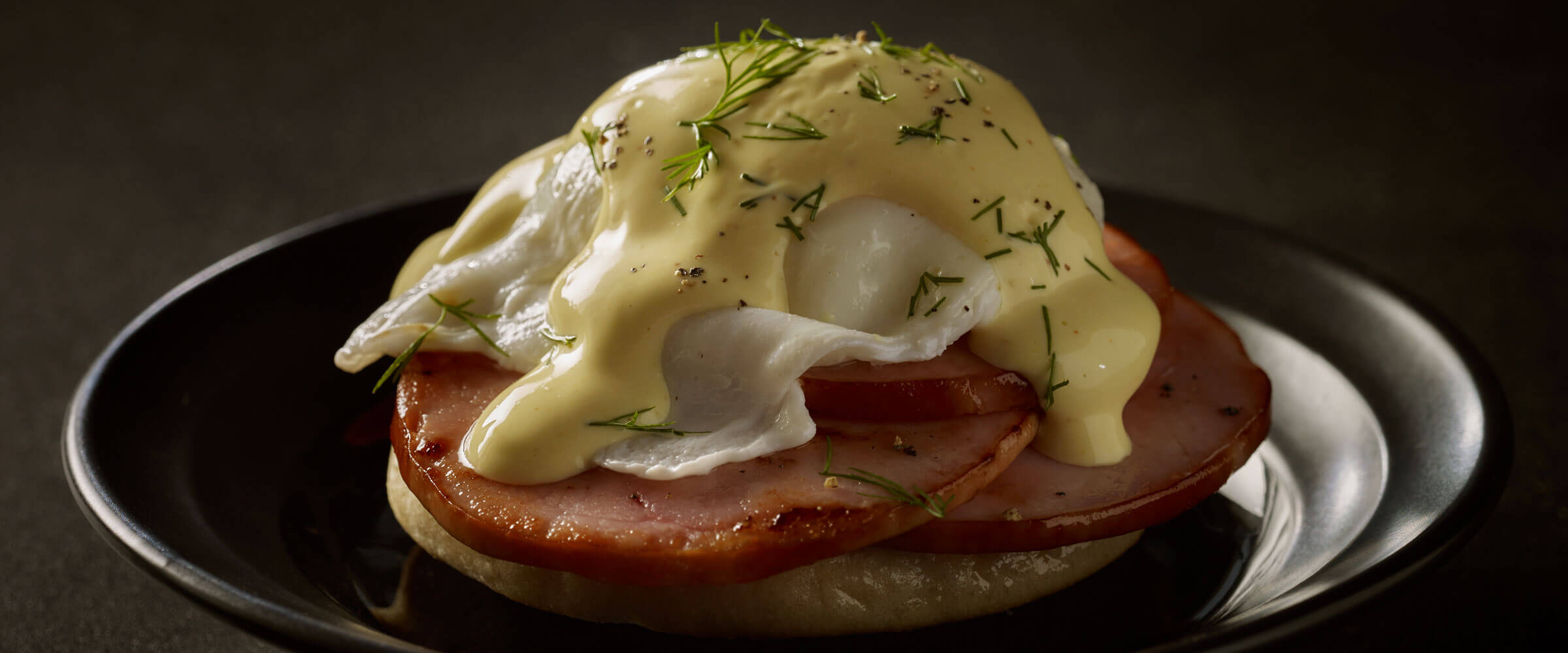 Canadian Bacon Eggs Benedict on black plate