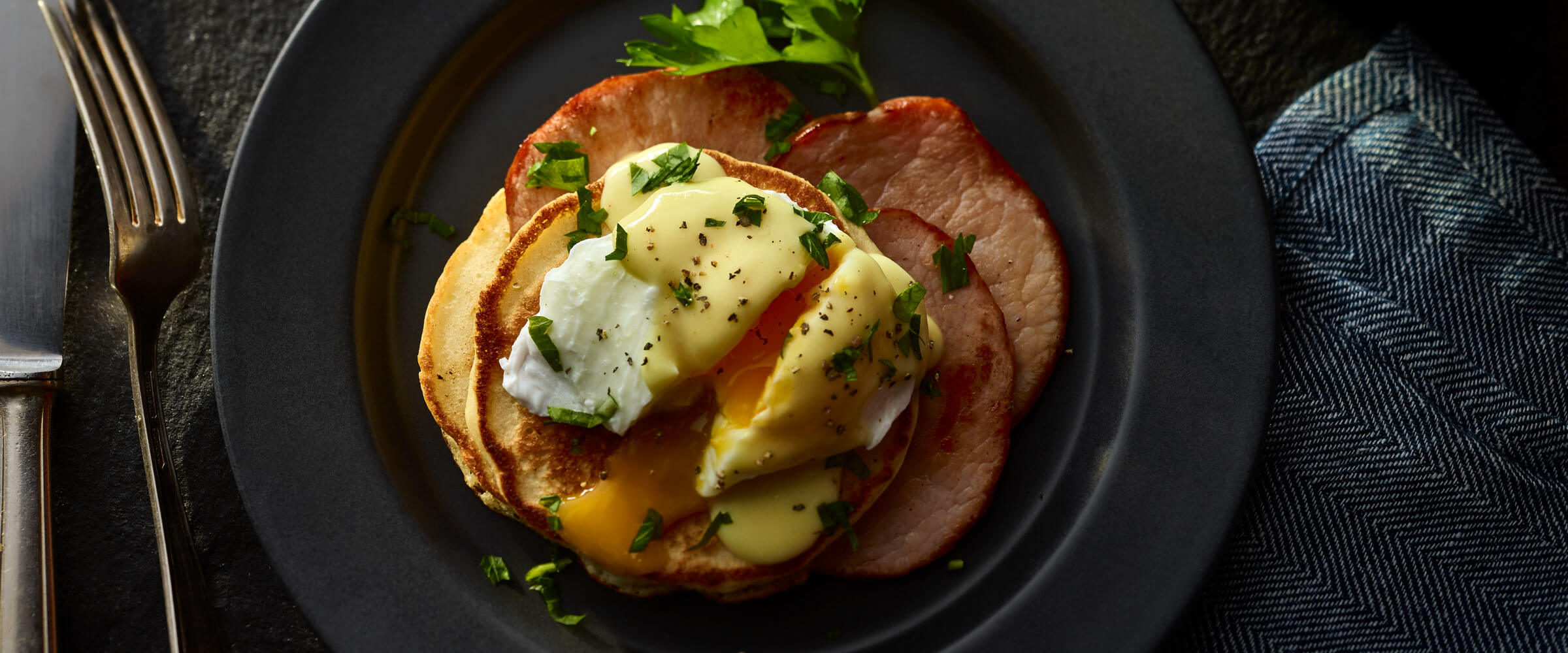 Pancakes Benedict with canadian bacon on black plate