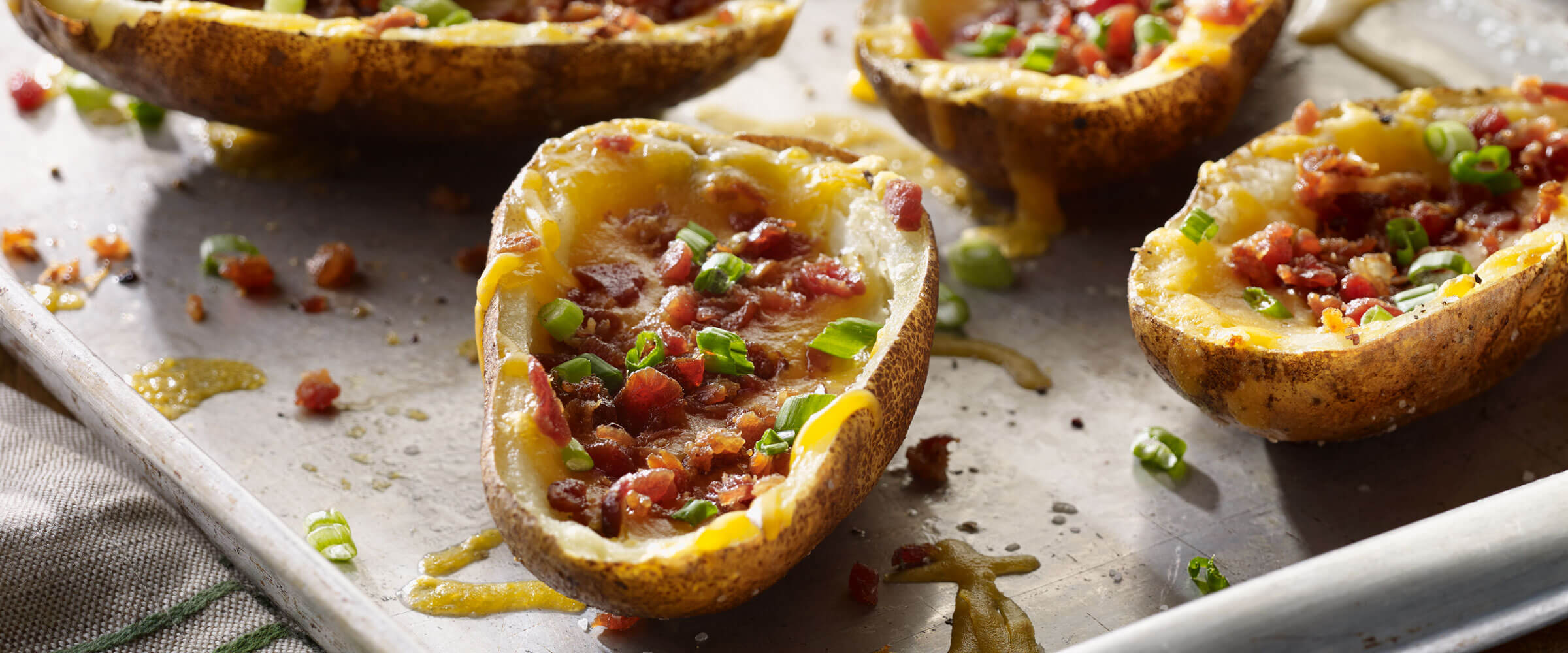 Game Day Potato Skins topped with bacon bits on sheet pan