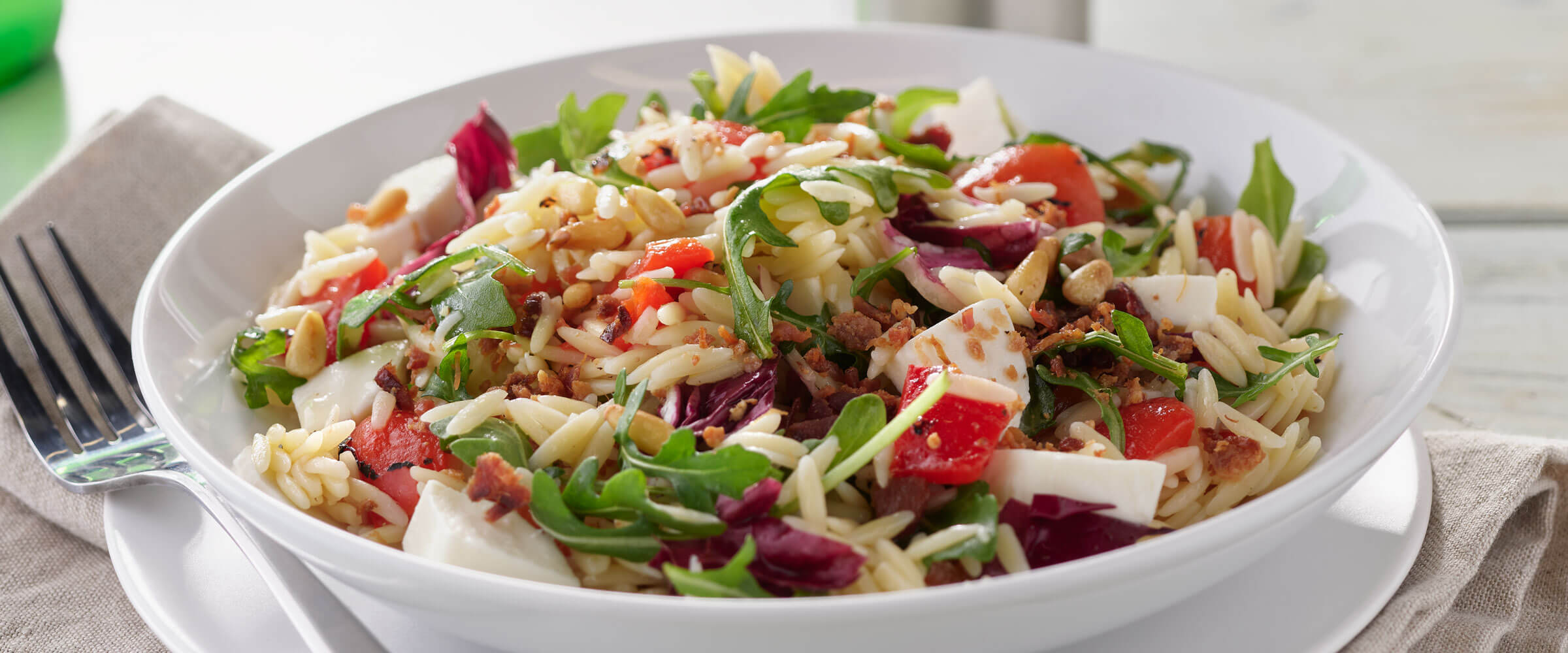 Orzo Salad with garnish in white bowl