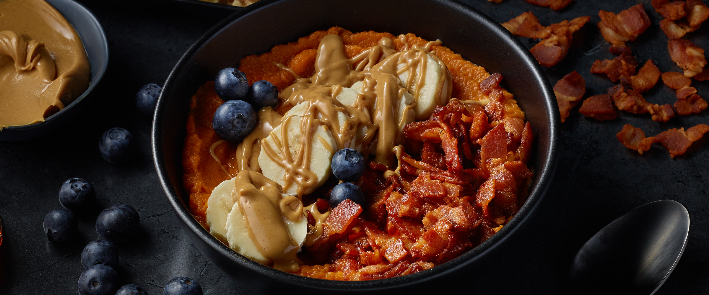 Sweet potato and bacon breakfast bowl in a small black bowl.