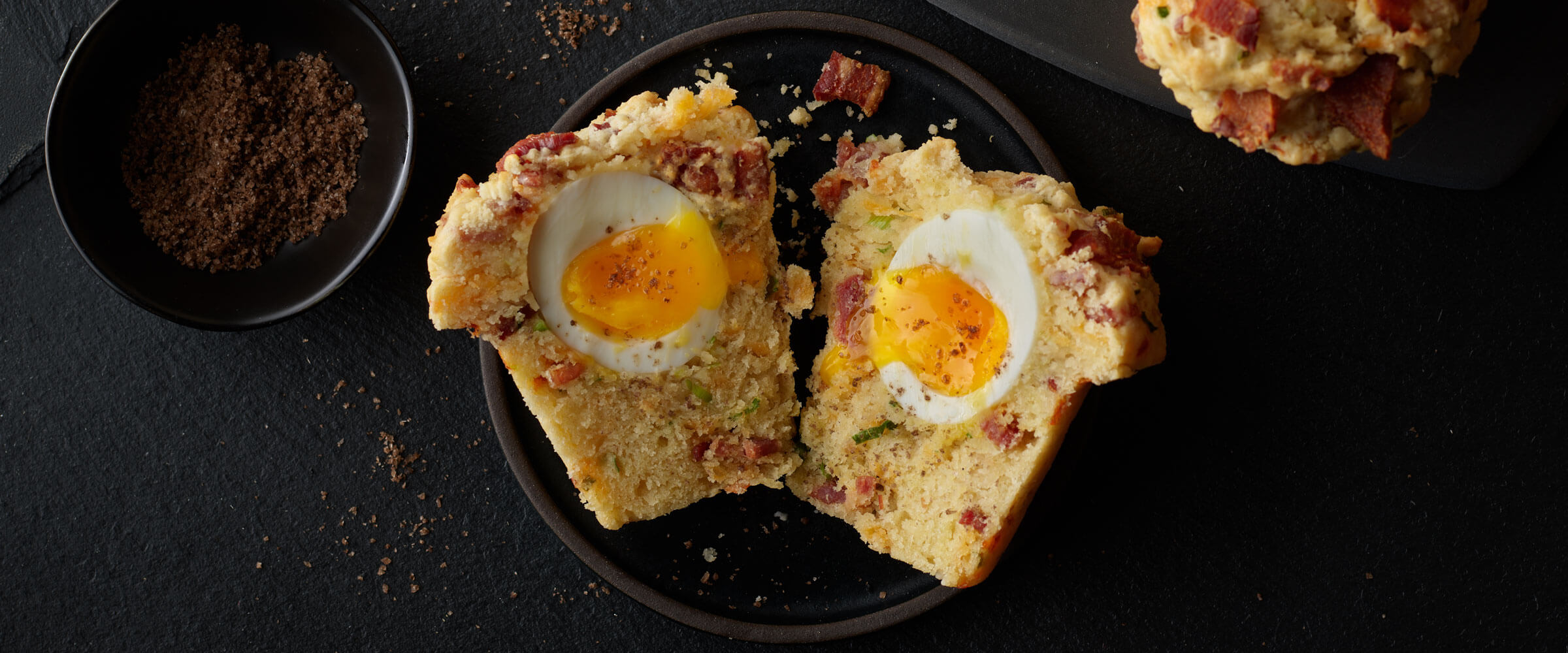 Bacon and Egg Breakfast Muffins cut open on black plate