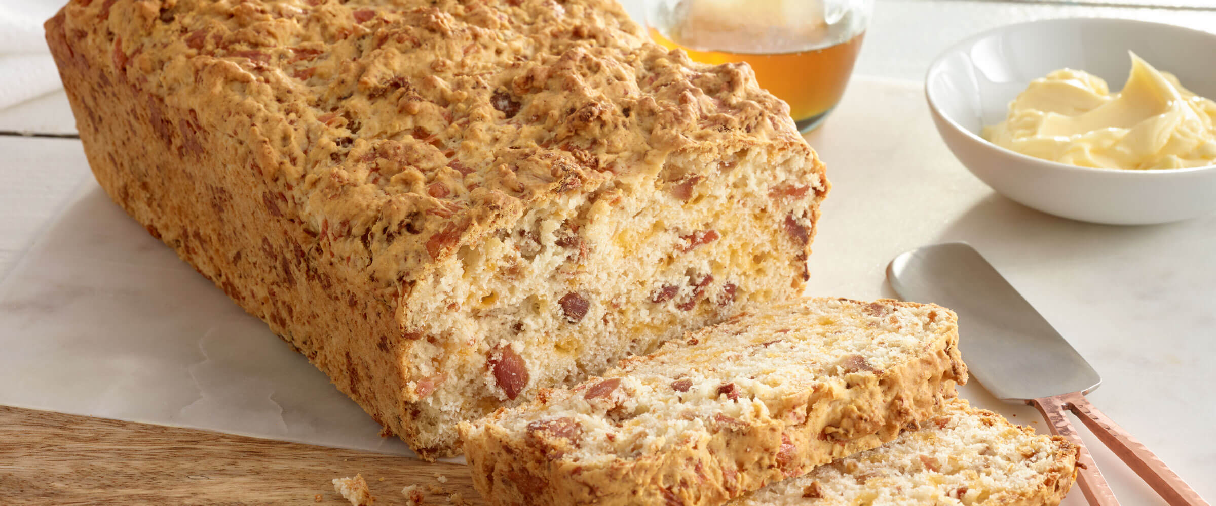Bacon-Beer Cheese Bread sliced with dish of butter