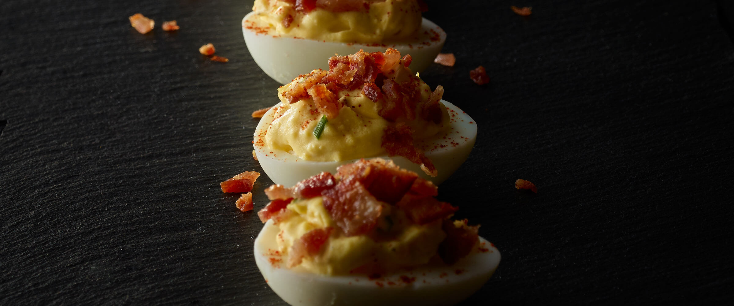 Bacon Topped Deviled Eggs on black platter