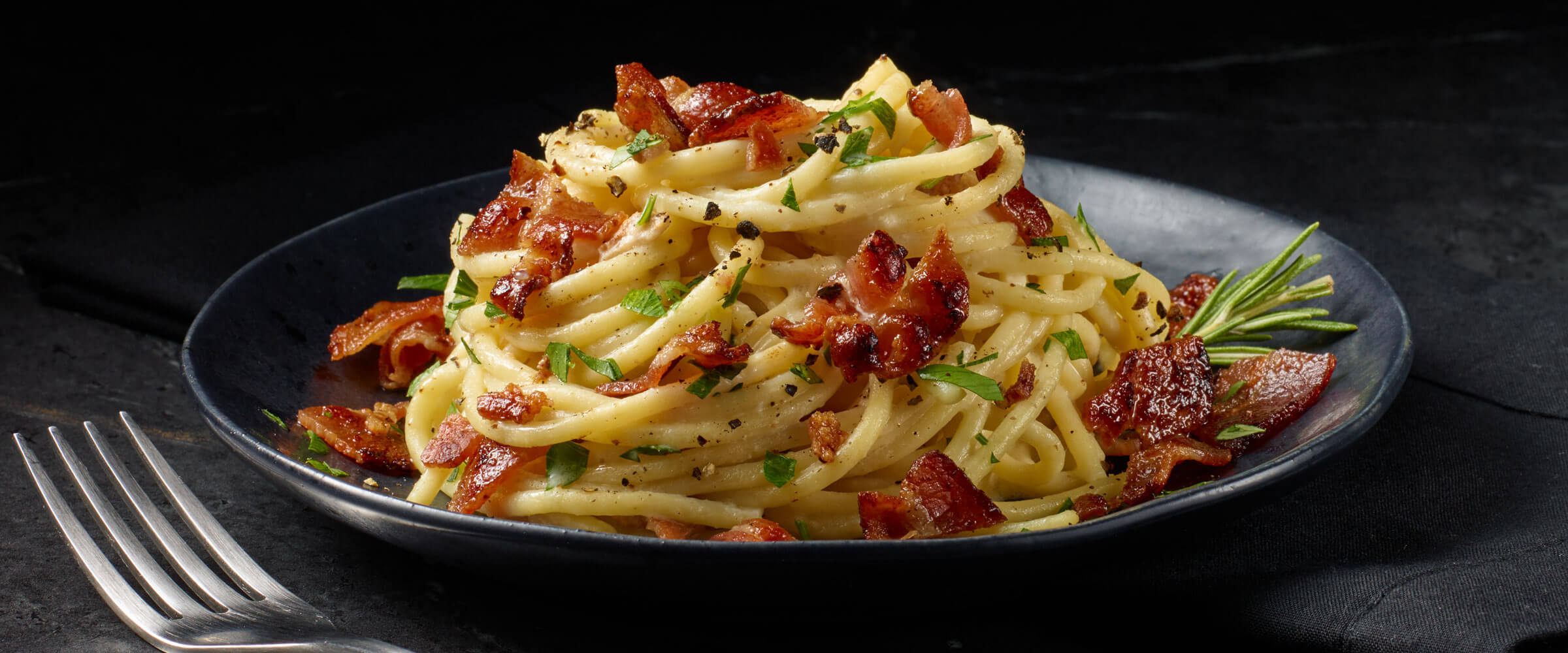 Creamy Pasta with Bacon in black bowl