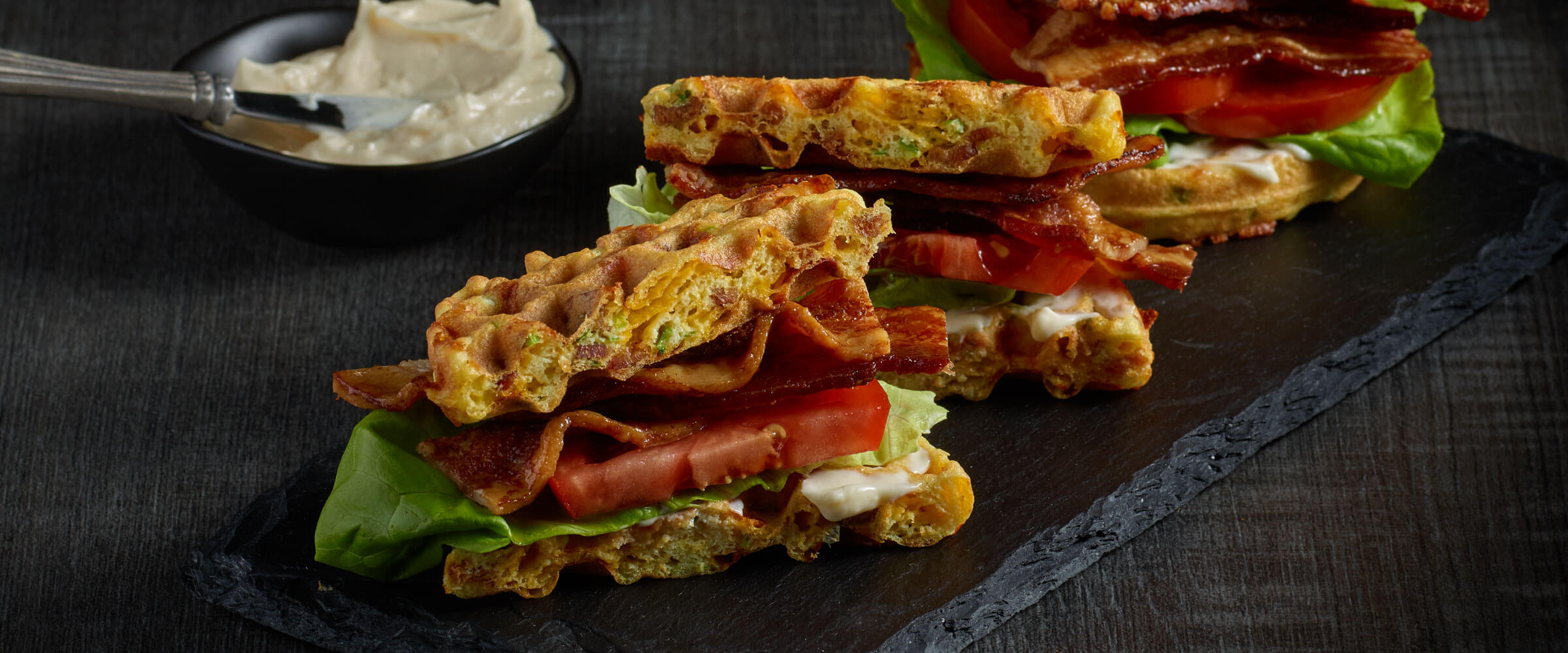 Chaffle BLT on black board with mayo on side