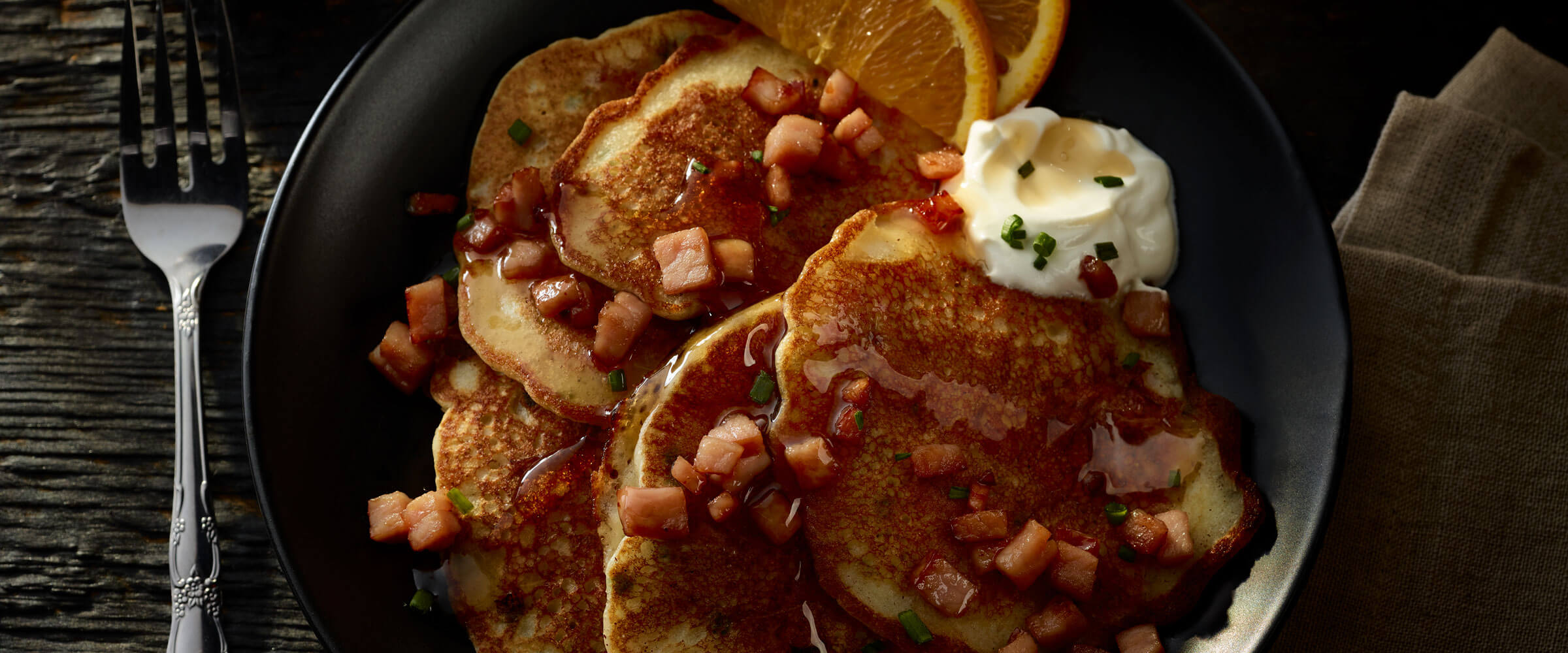 Canadian Bacon Pancakes topped with chives on black plate