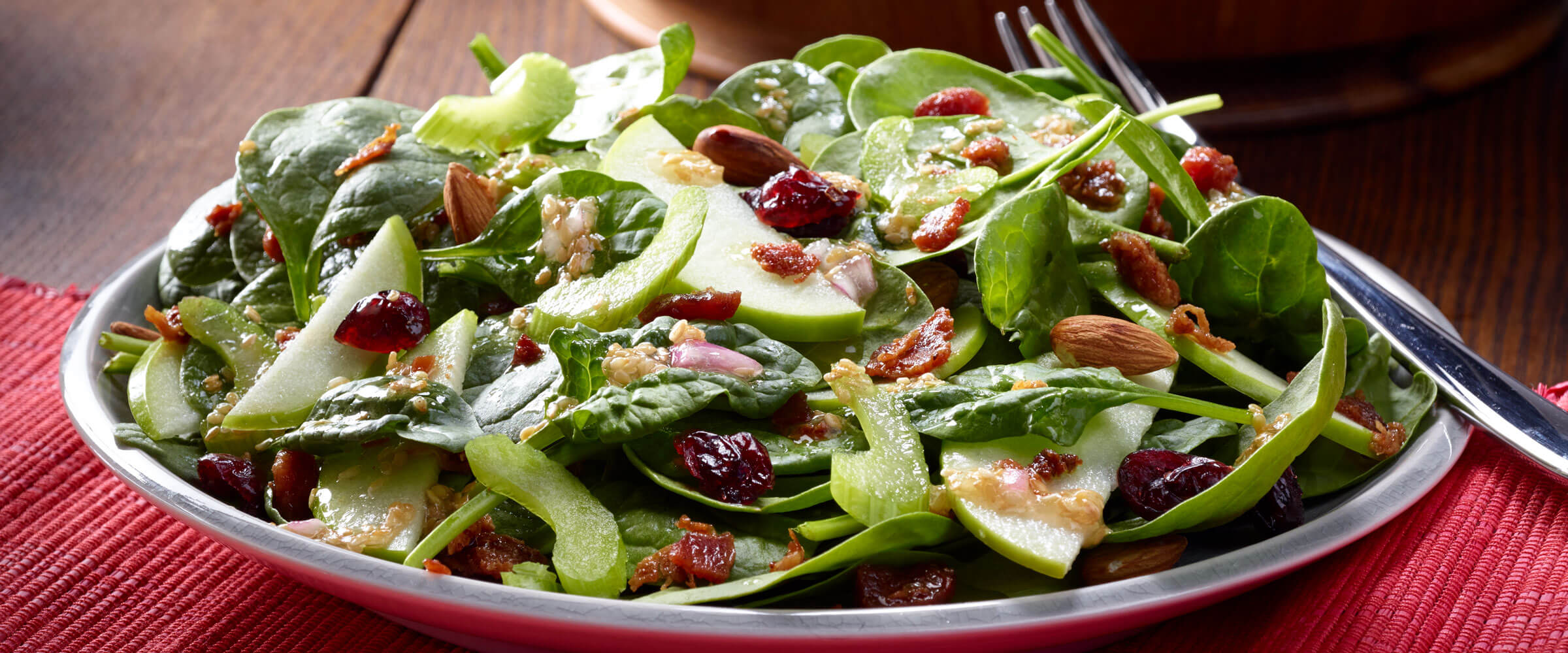 Cranberry Almond Bacon Salad with apples on plate on red placemat