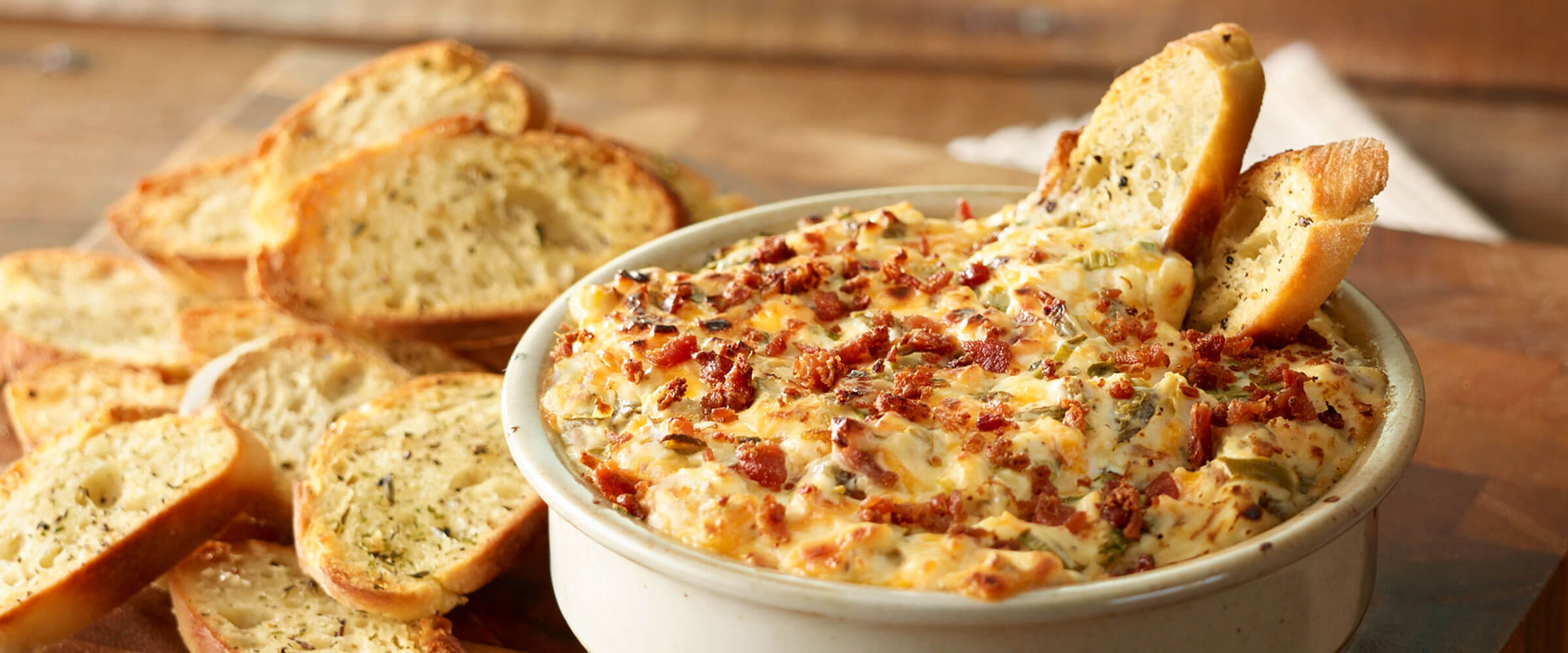 Jalapeño-Bacon Popper Dip in bowl with crostini slices for dipping