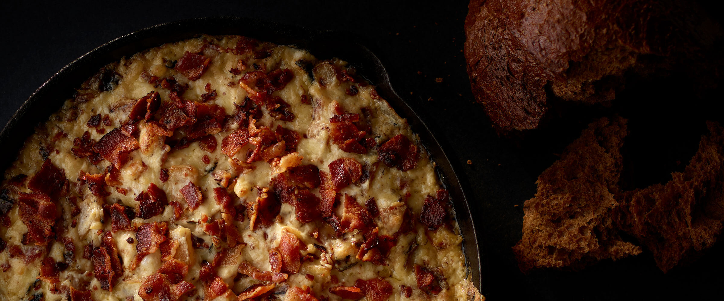 Smokey Bacon Onion Dip in cast iron skillet with bread for dipping