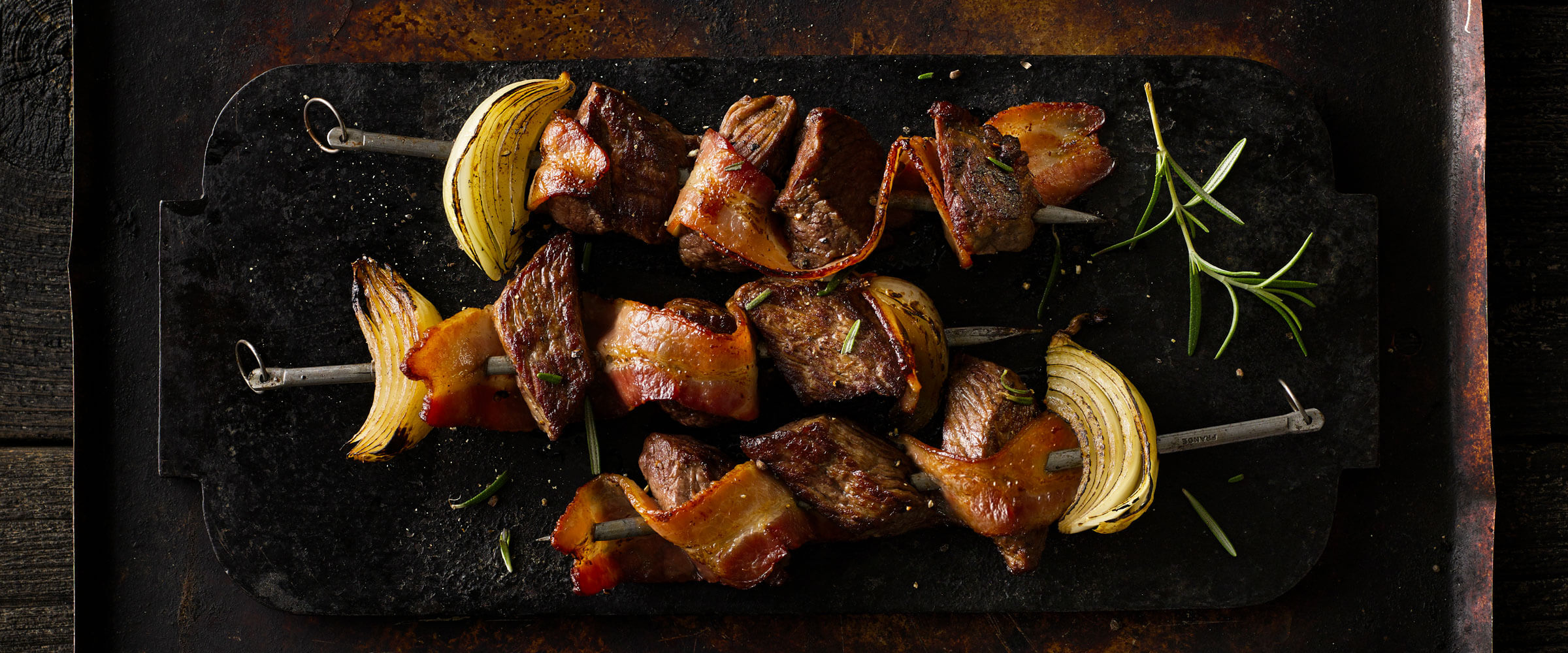 Cherrywood Bacon Steak Kebobs on black platter with garnish