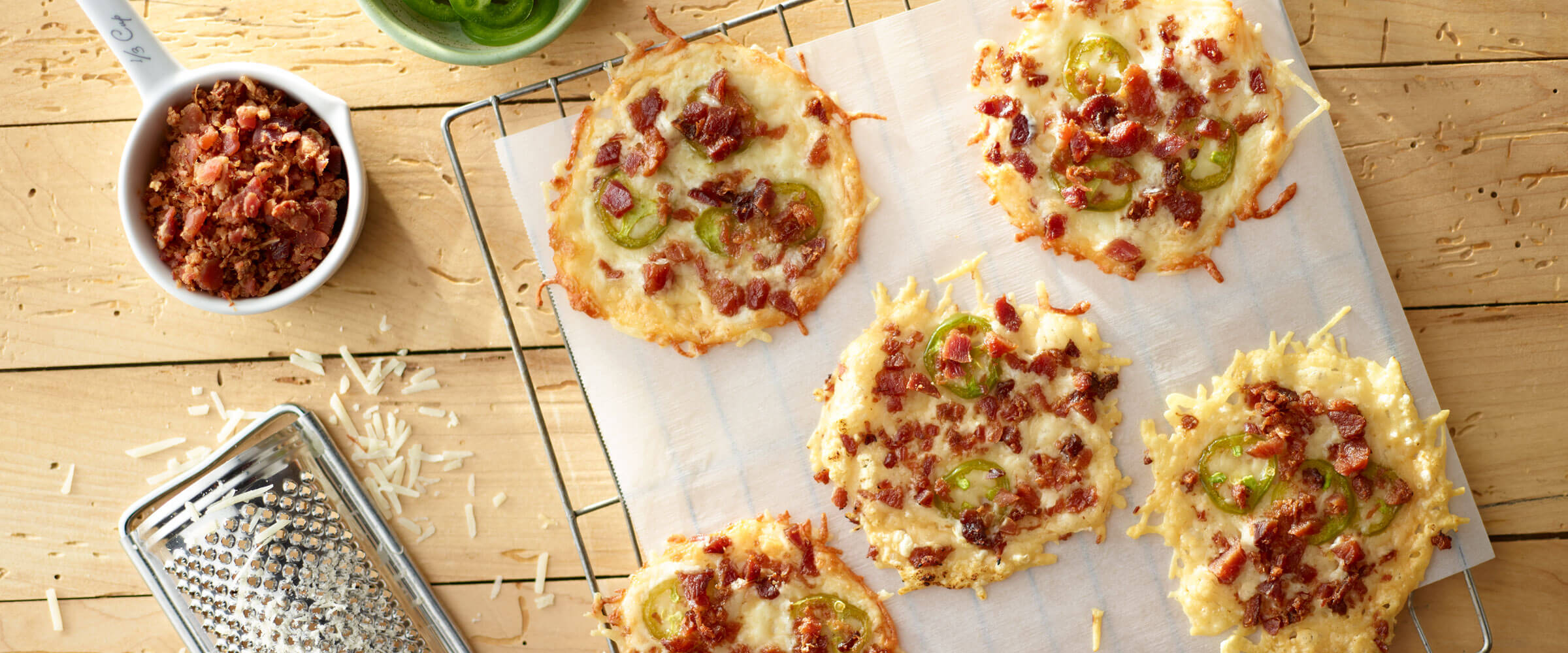 Cheese & Jalapeño Bacon Crisps on parchment paper with extra bacon bits on side
