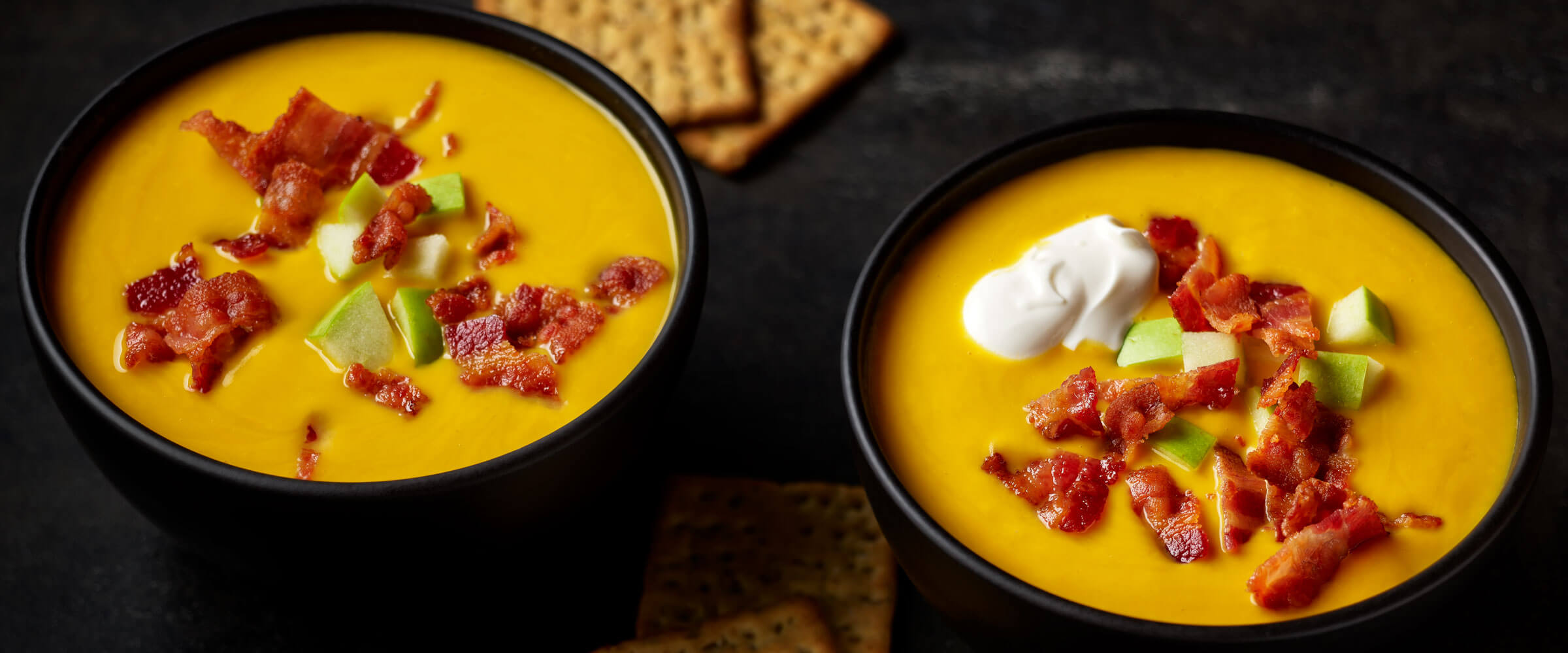 Butternut Squash Soup with Bacon, Apple and Sour Cream in black bowls