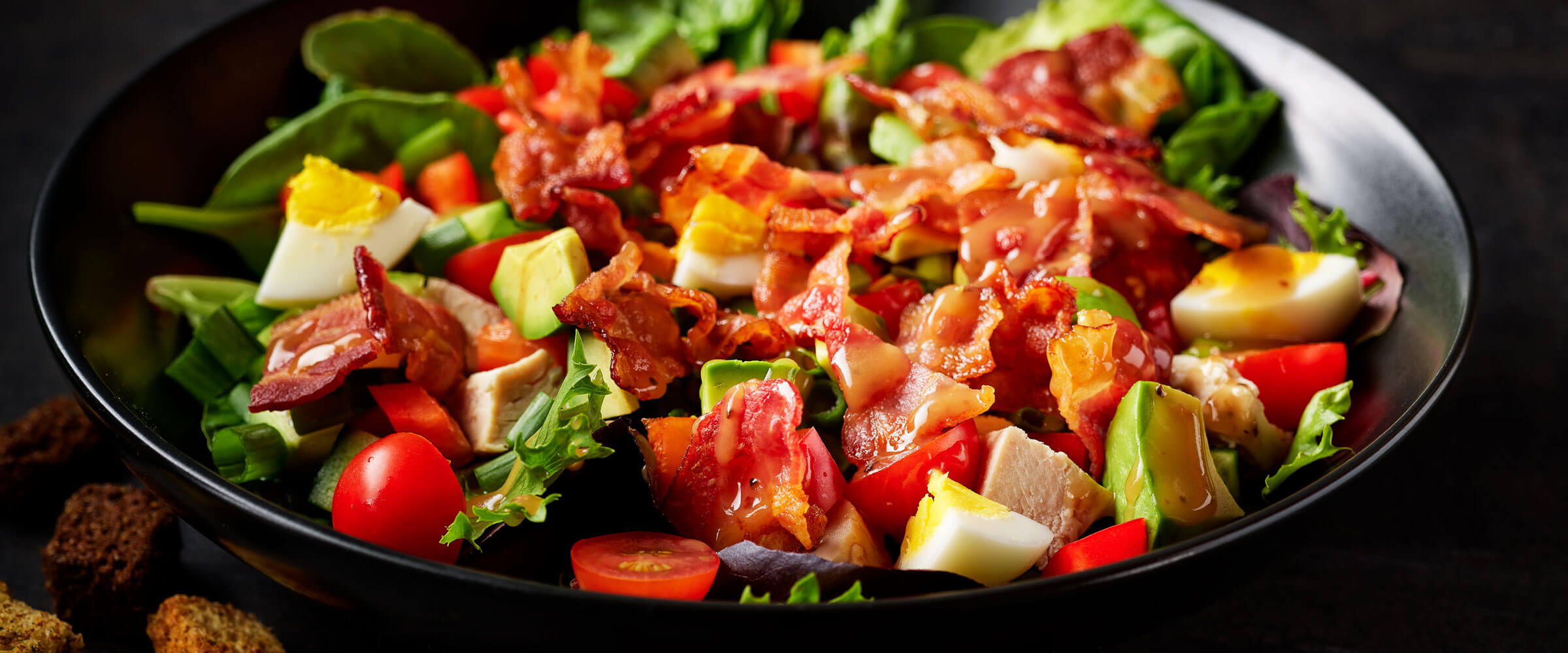 Microwave Bacon Dinner Salad with avocado, egg and tomato in black bowl