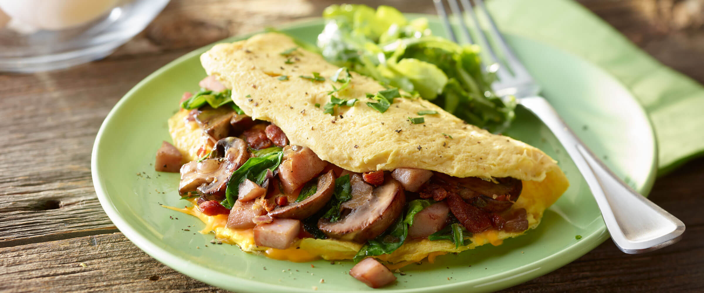 Bacon, Ham and Cheese Omelet with mushrooms on green plate