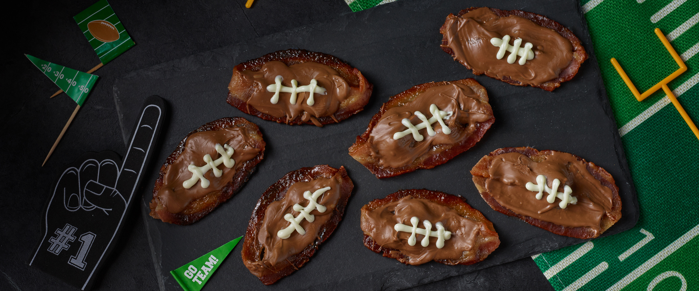 Chocolate covered bacon in the shape of footballs with white chocolate icing for the laces