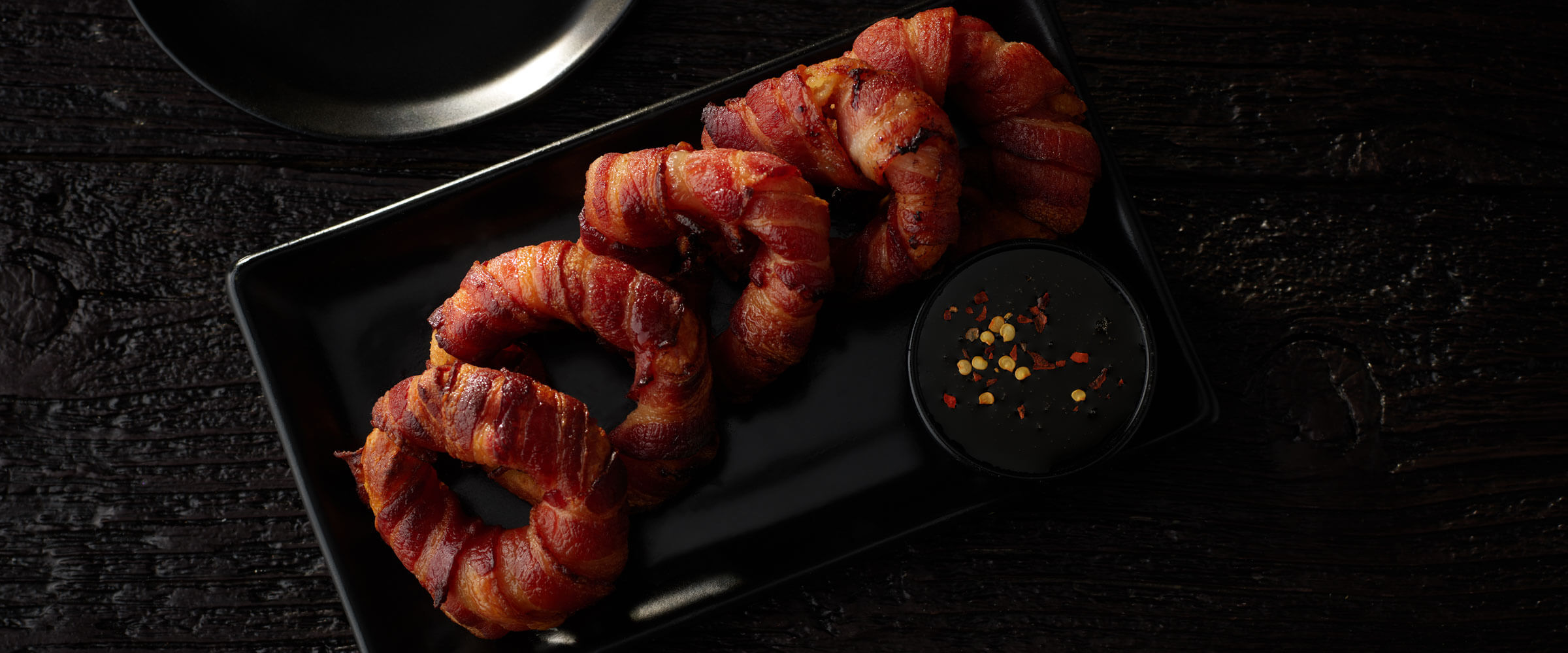 Bacon Wrapped Onion Rings on black plate
