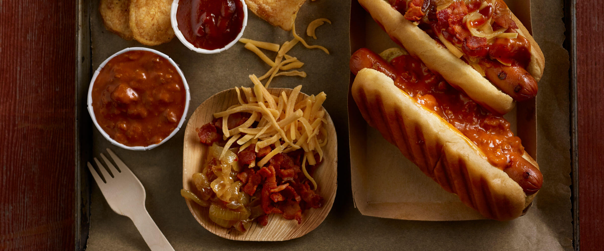 Cowboy Dogs topped with onions, bacon and cheese with extra toppings on side