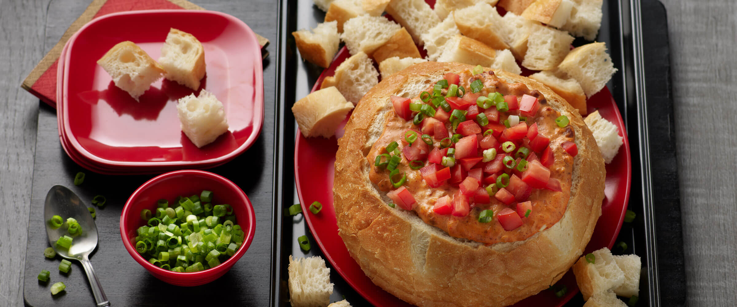 Sourdough Chili Dip topped with tomatoes and green onions with pieces of bread for dipping