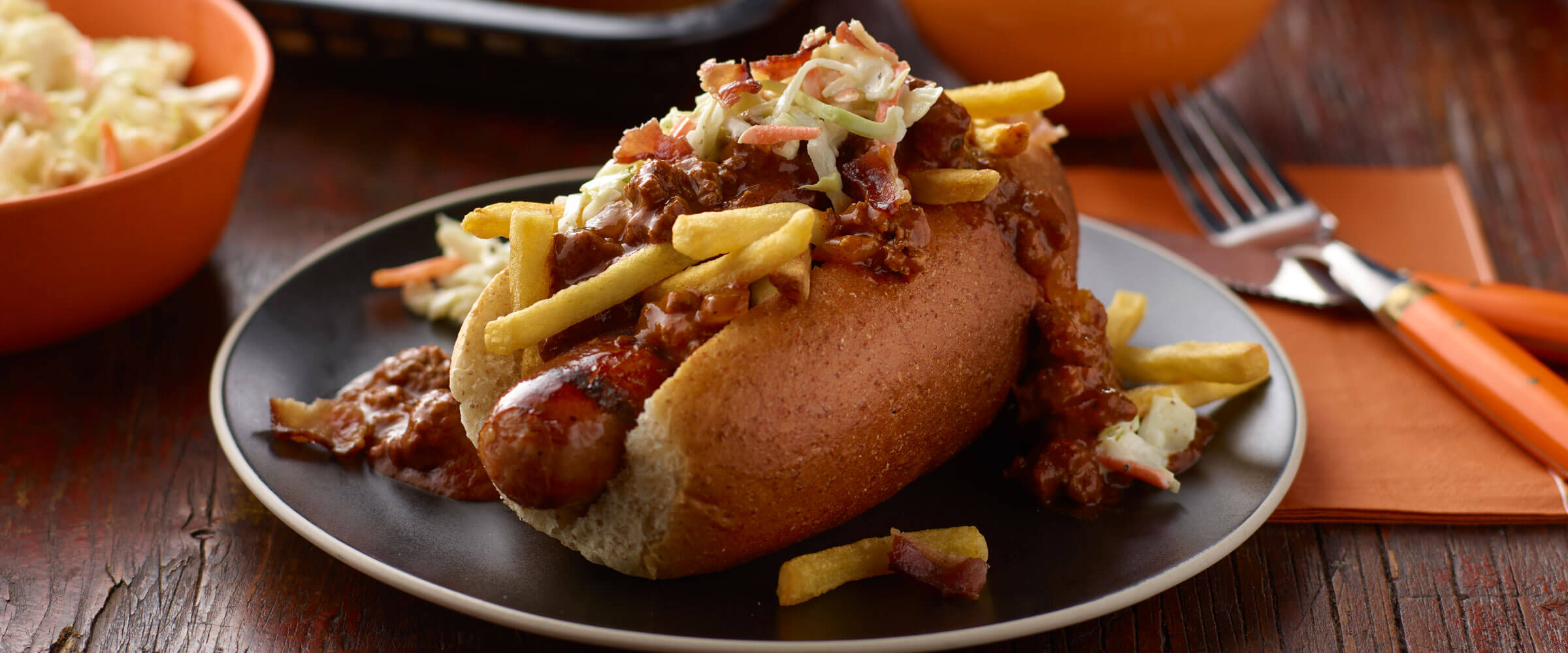 Cleveland Chili Grilled Kielbasa Sausage Sub topped with fries and slaw on black plate