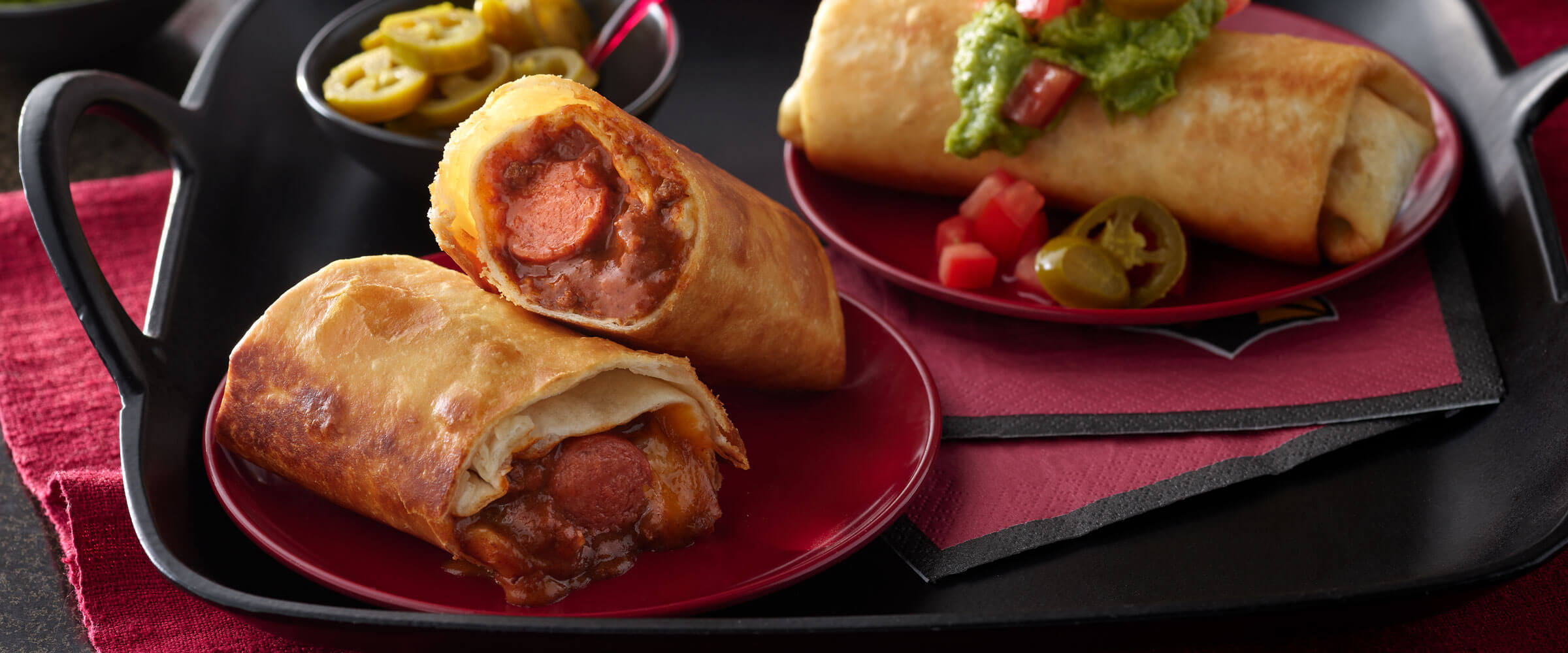 Chili Cheese Dog Chimichangas on black platter with red napkins