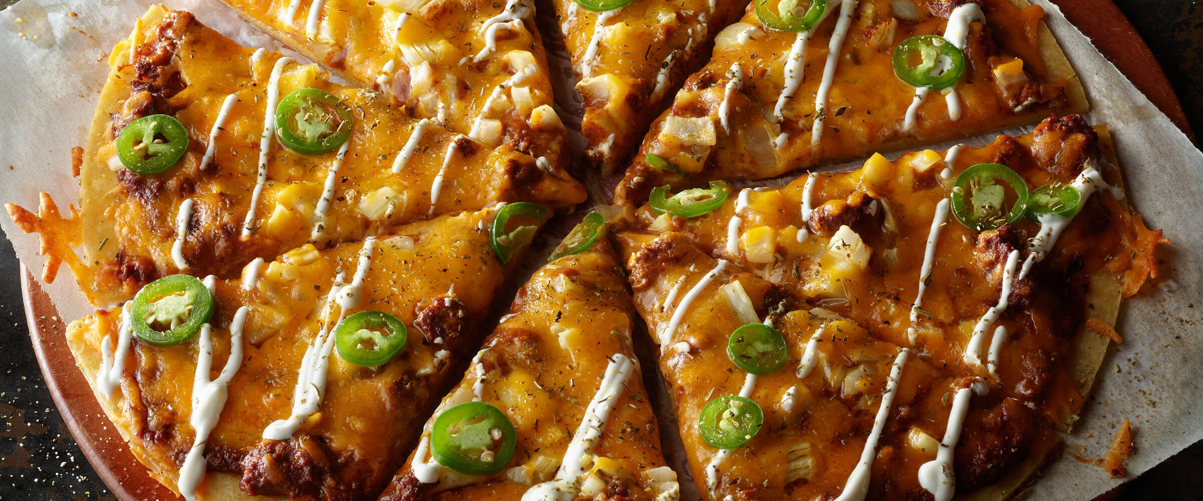 Chili Pizza Delight on pie pan topped with sour cream drizzle and jalapenos