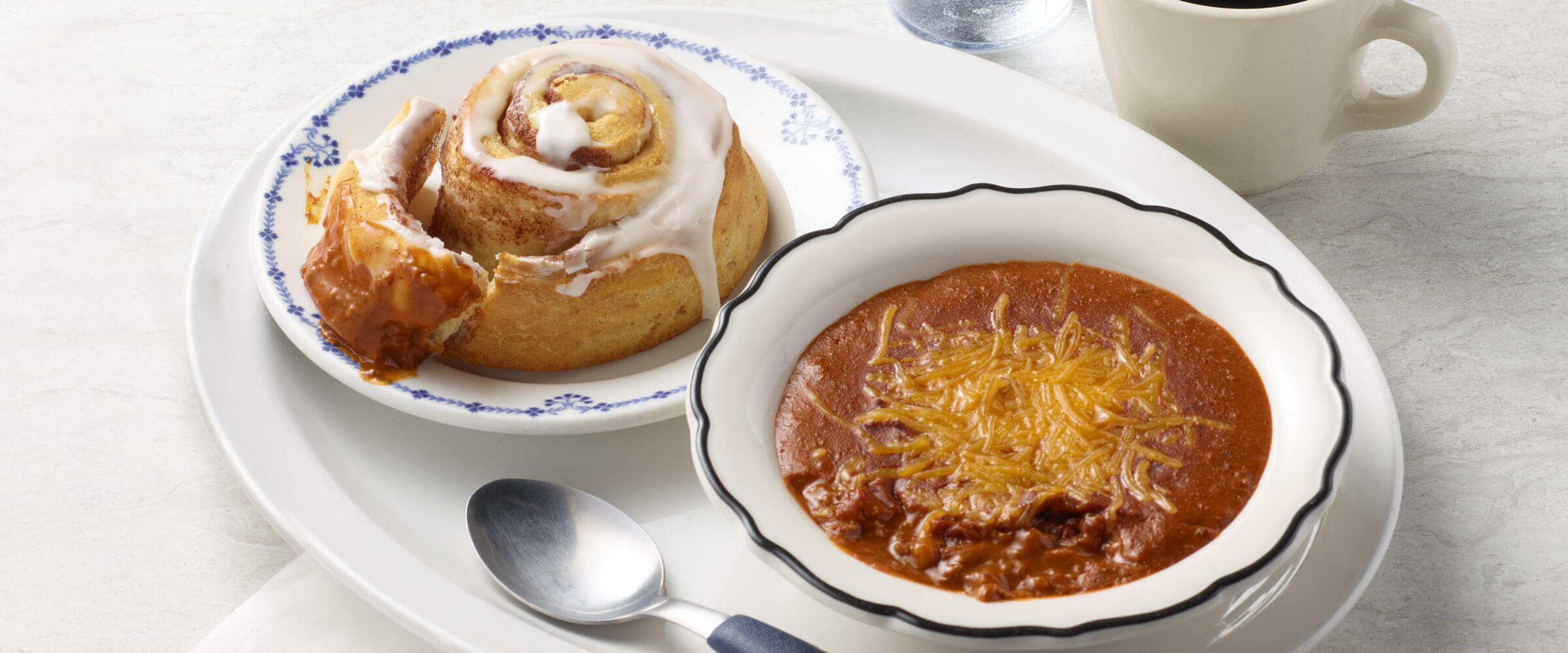 Chili topped with cheese and Cinnamon Roll on white dishes