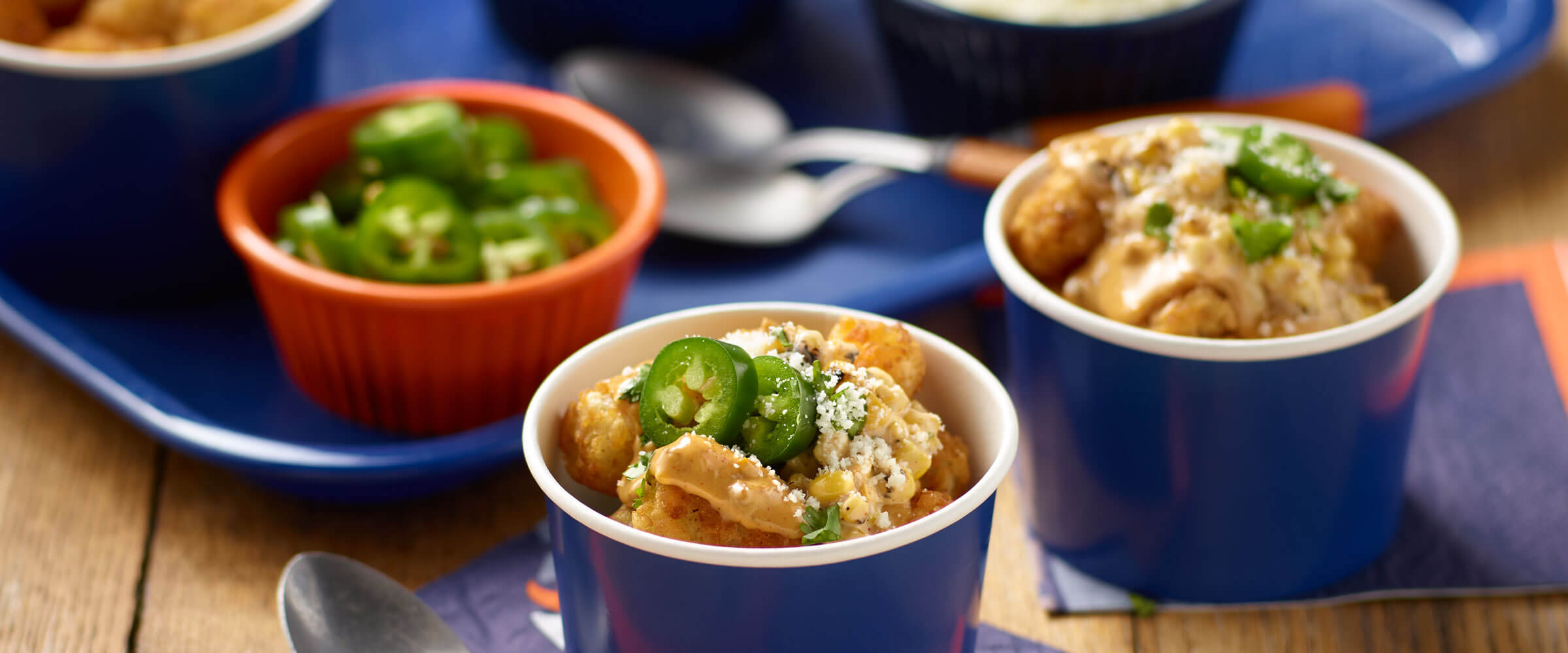 Elote Tots in individual blue bowls topped with jalapenos