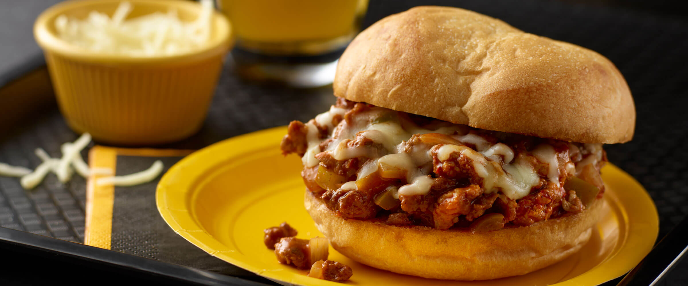 Hot Sausage Chili Sloppies on a yellow plate with extra cheese on the side