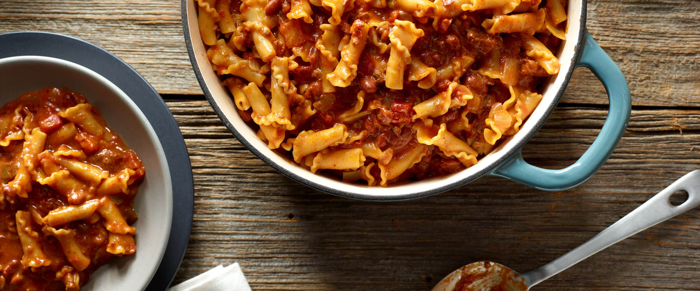 One Pot Chili and Cheese Pasta in blue dish with serving in a bowl