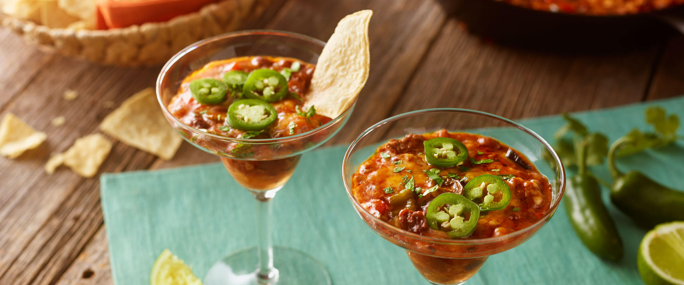 Queso Fundido Con Chili a la Tequila in martini glasses topped with jalapeno and chips on the side