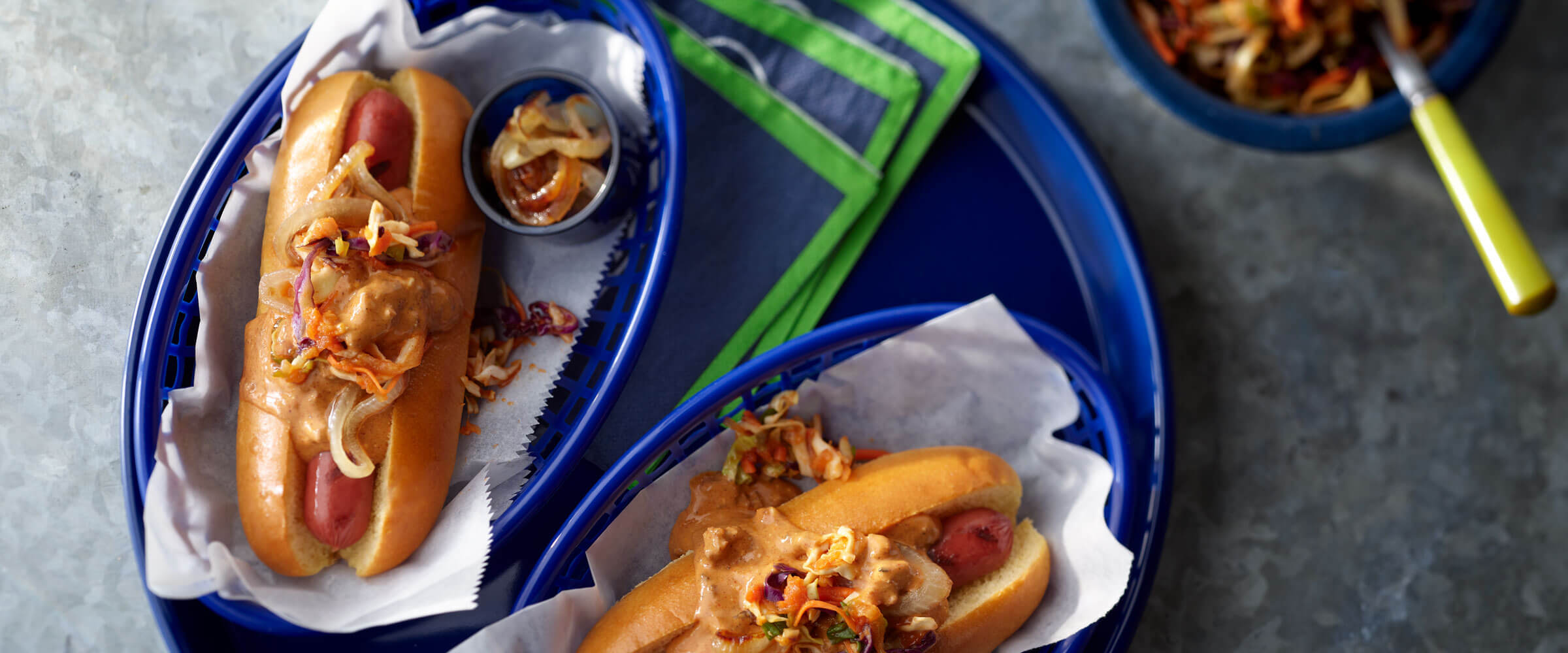 Seattle Chili Dog topped with onions and and sauce in blue baskets