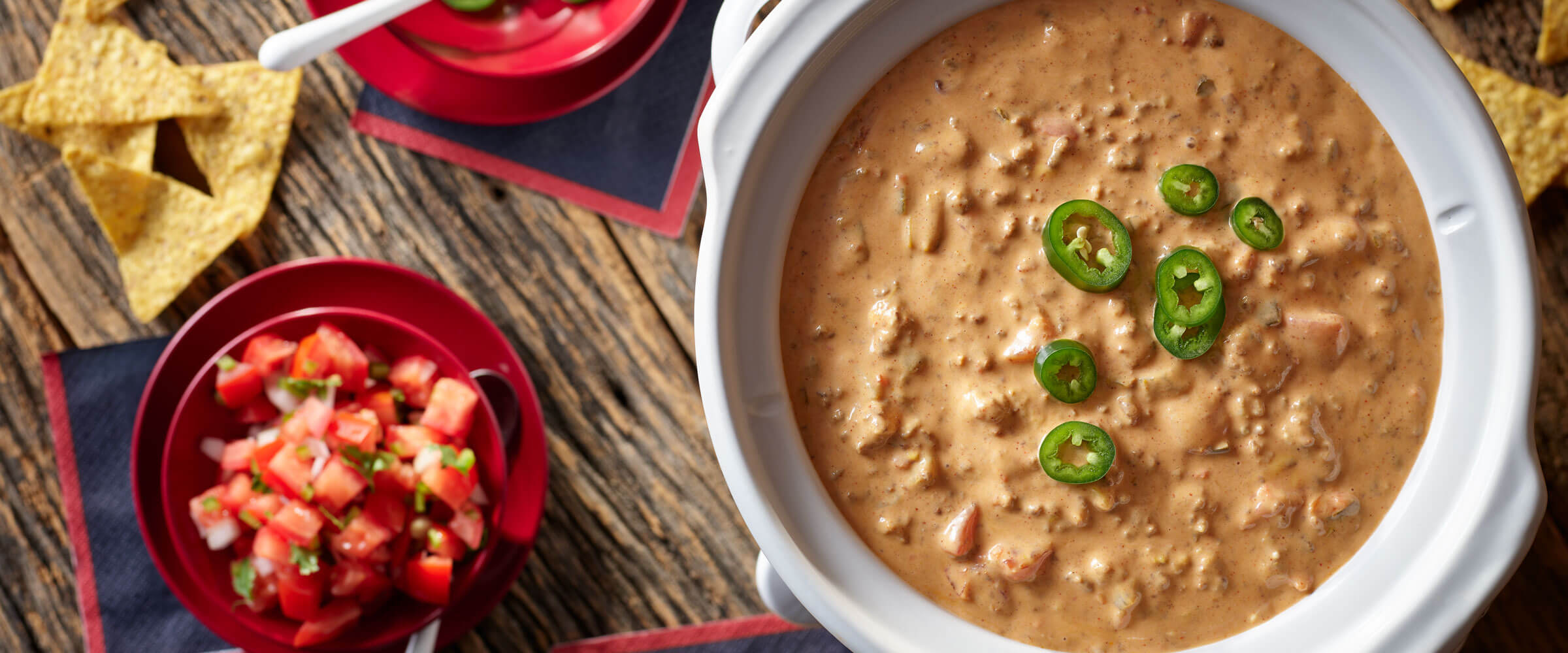 Slow Cooker Chili con Queso Dip topped with jalapeno in white dish with salsa on the side