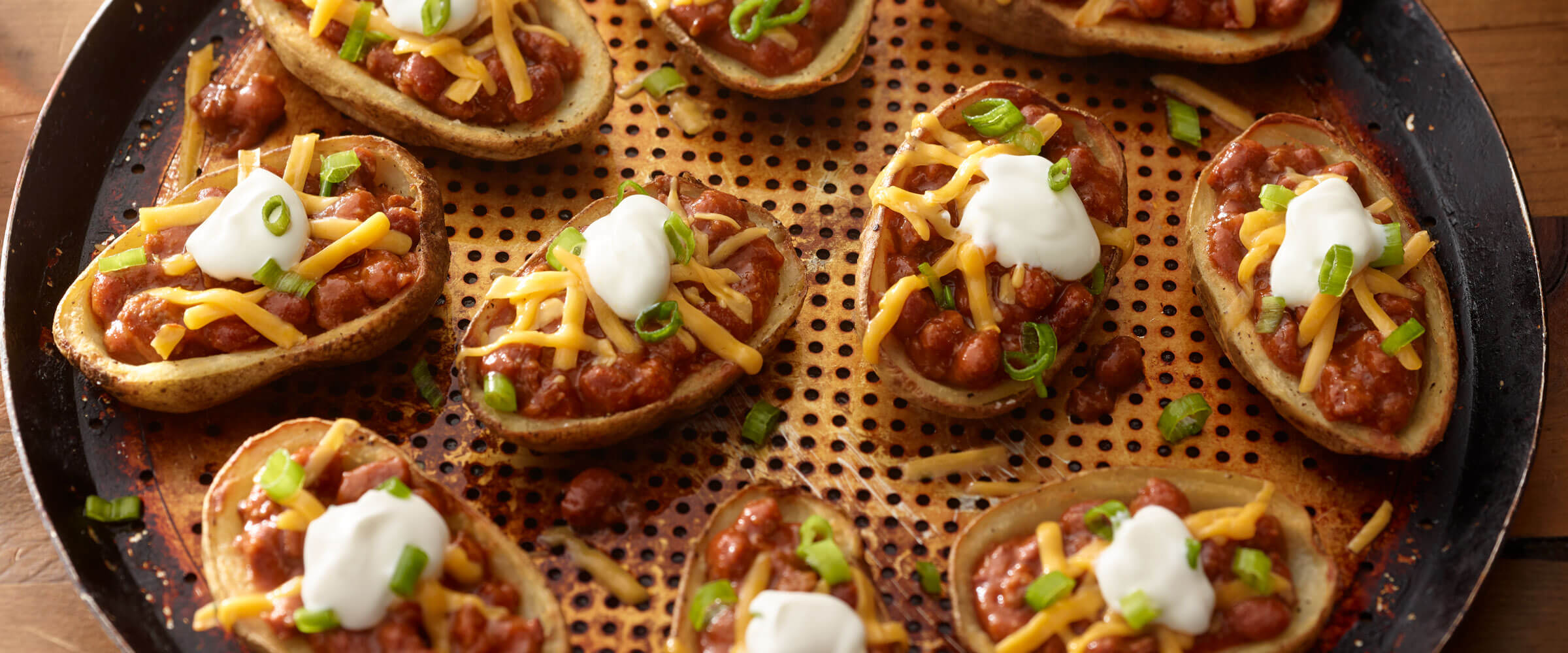 Super Loaded Chili Potato Skins topped with sour cream and cheese on metal pan