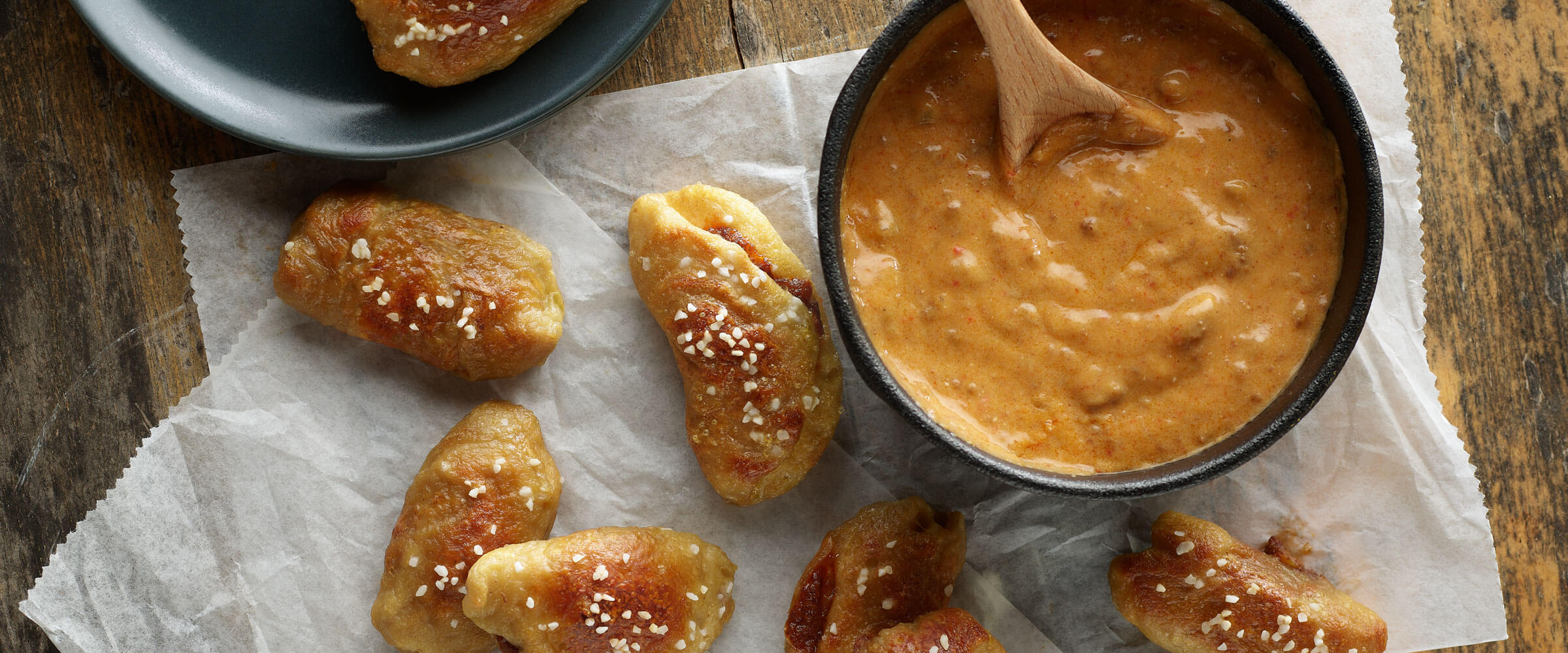 Chili Stuffed Pretzel Bites with Chili Cheese Dip on parchment paper with serving spoon