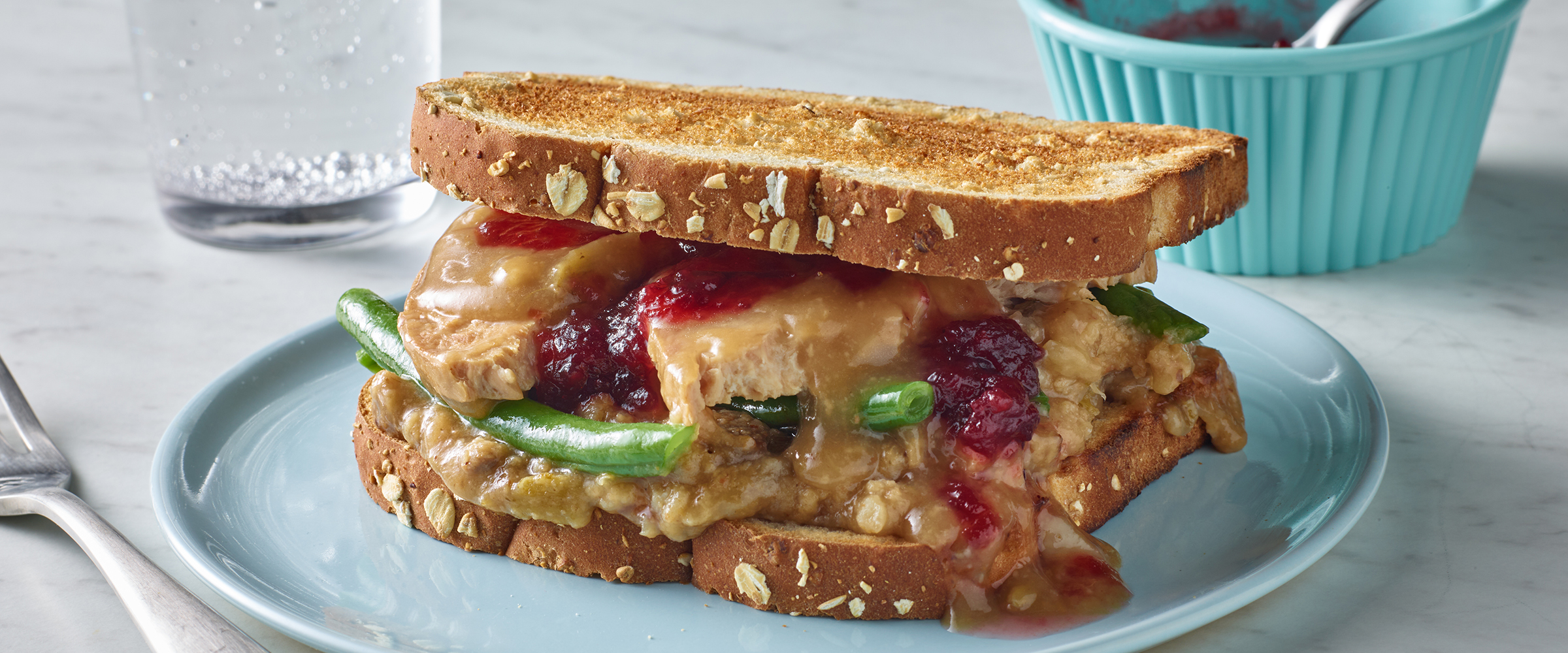 Turkey Dinner Sandwich with gravy and cranberry sauce spilling onto the plate.