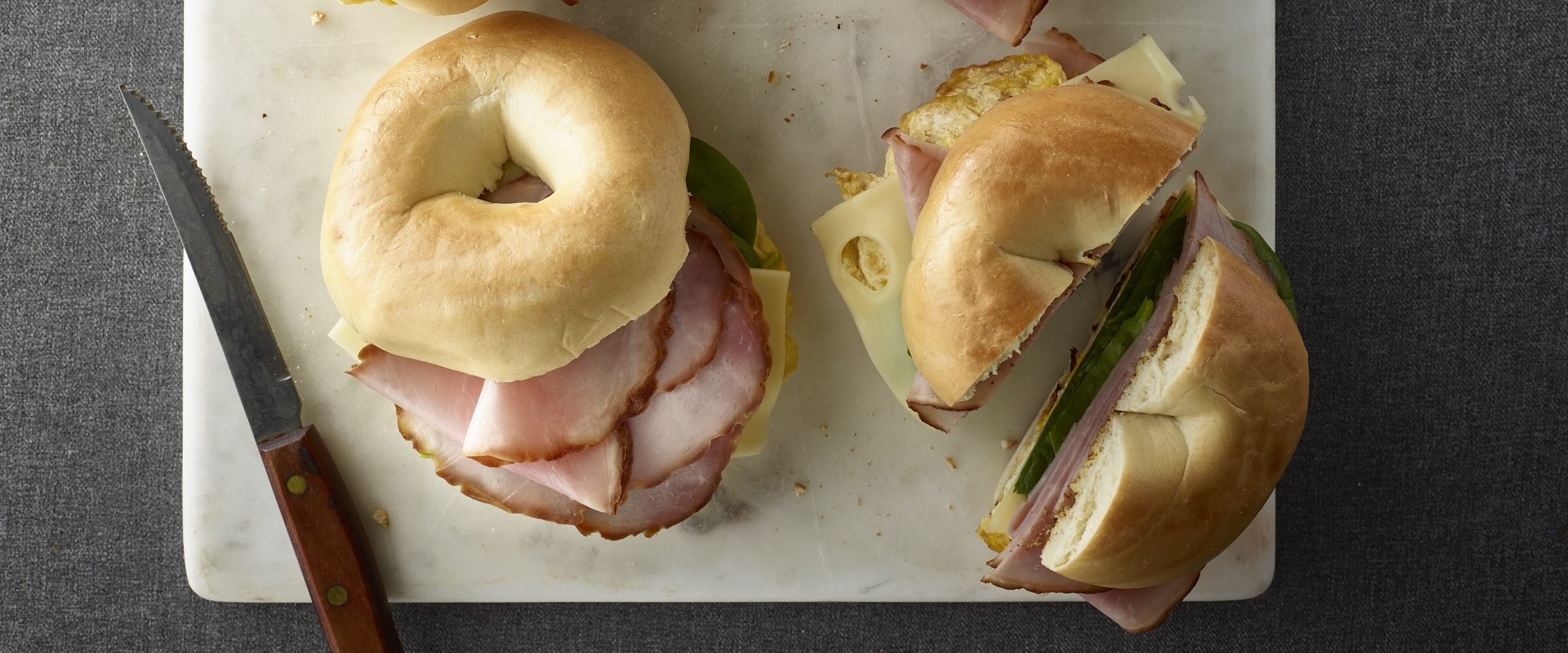 Cure 81 ham and cheese breakfast bagels on white board with knife
