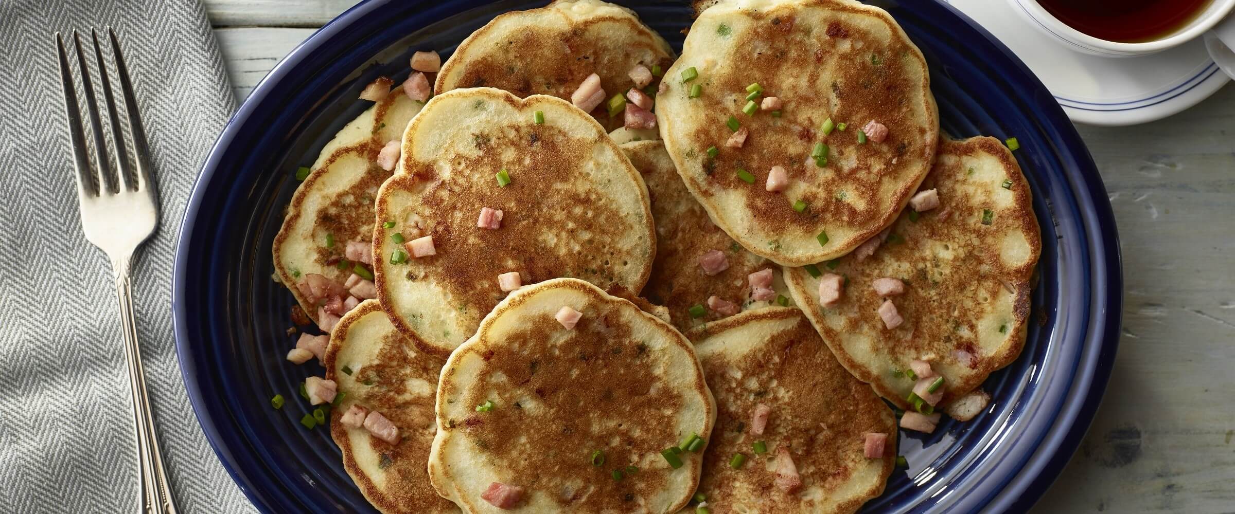 Cure 81 ham and cheese potato pancakes on blue dish with fork