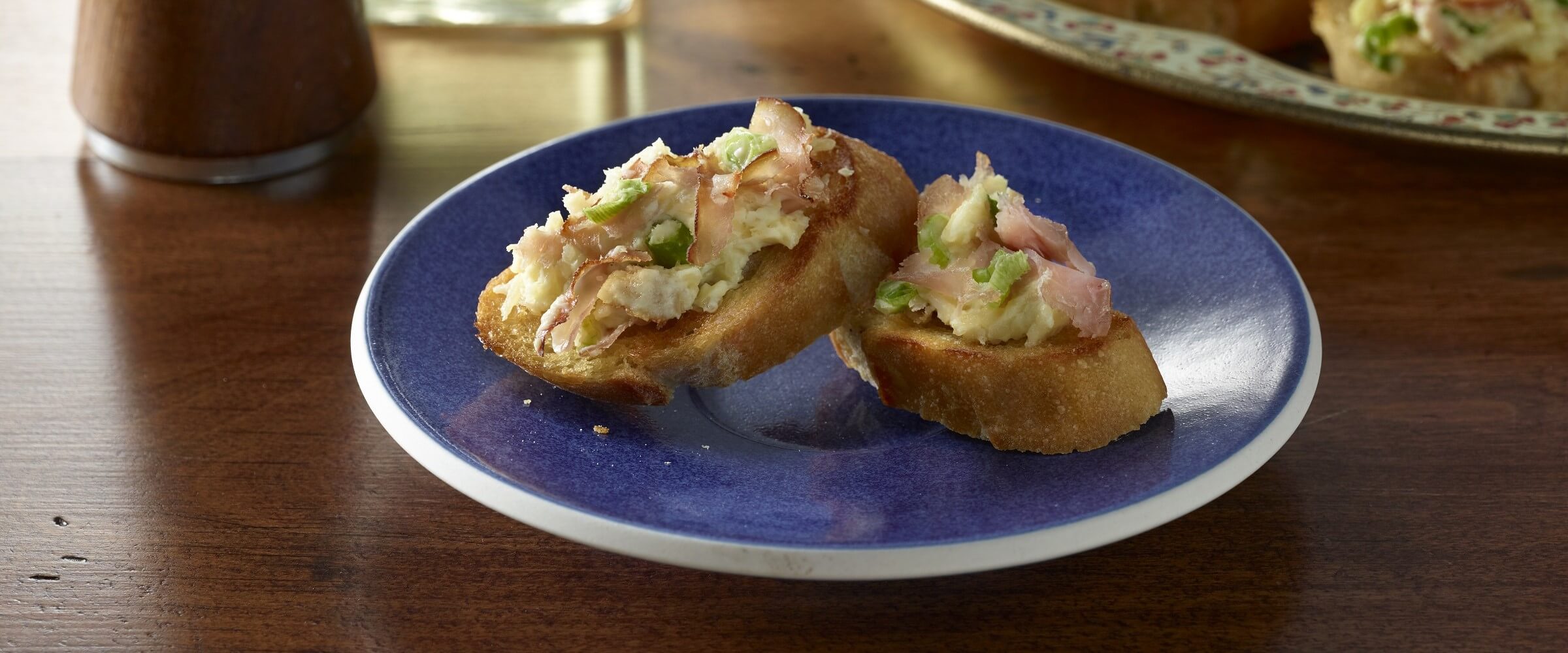 ham and parmesan appetizer on crostini on blue plate