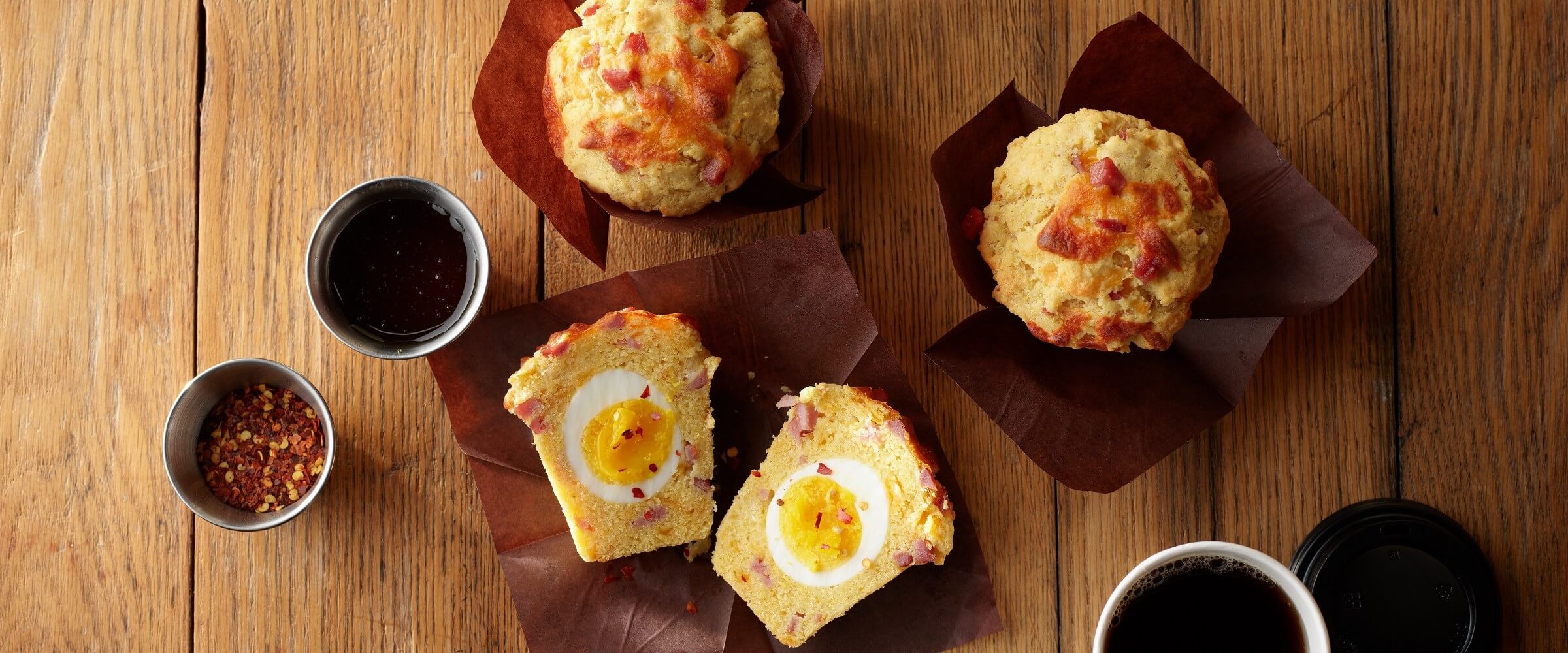Cure 81 ham and cornbread breakfast muffins on wood table with dipping sauce