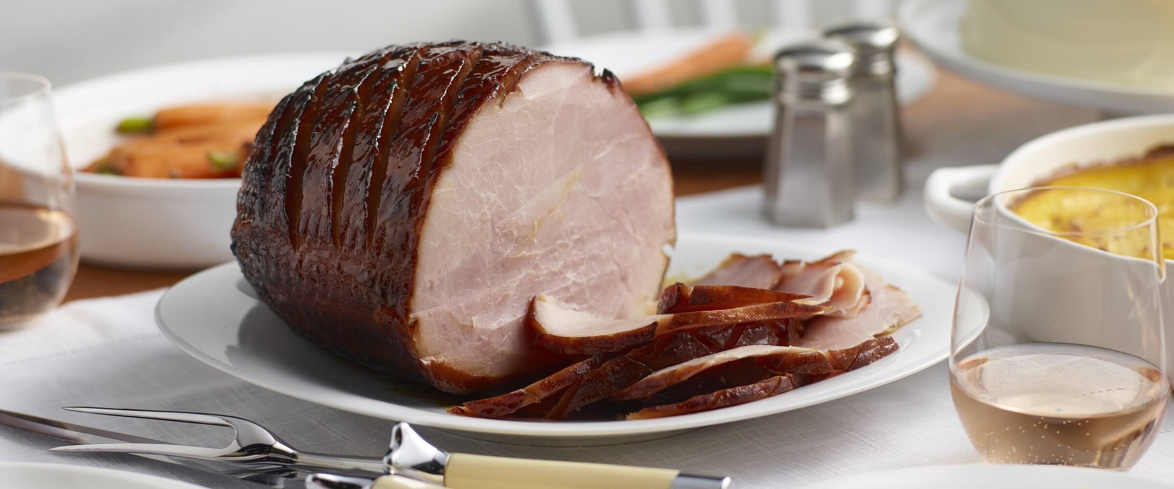 Cure 81 balsamic dijon glazed ham sliced with drink and bowls with sides